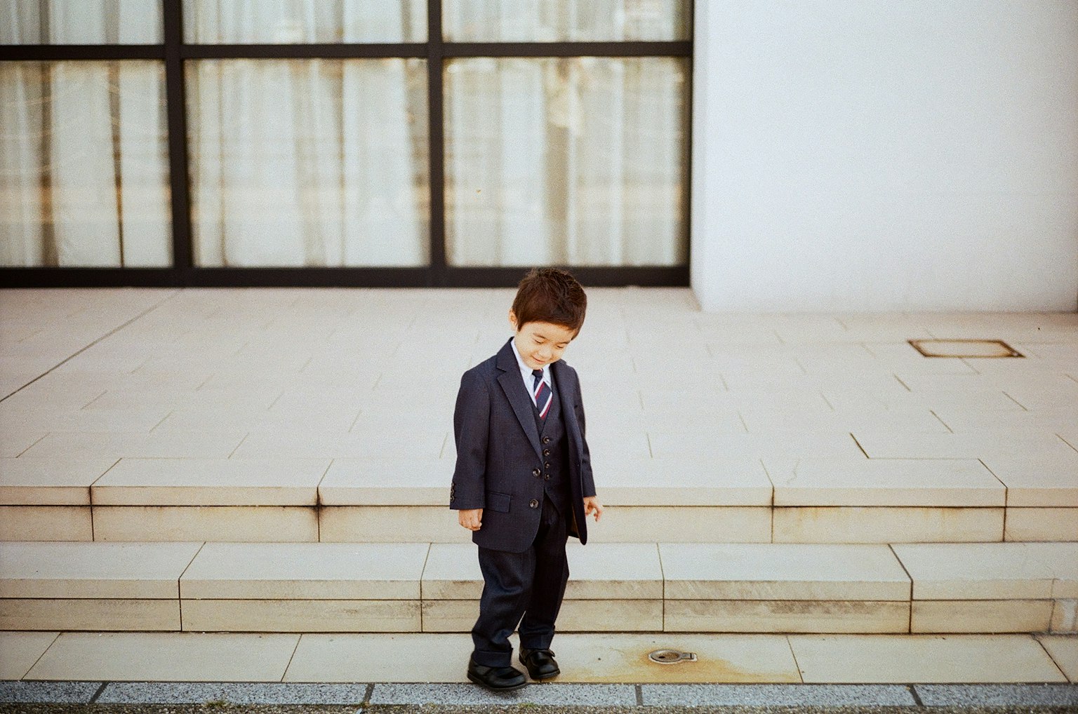 A boy in a suit standing in front of stairs