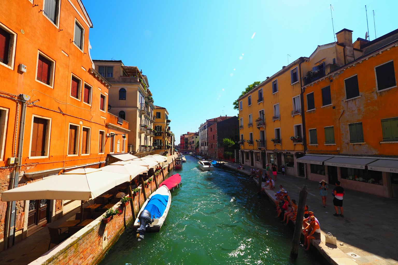 Những tòa nhà màu cam sáng dọc theo kênh Venice dưới bầu trời xanh trong