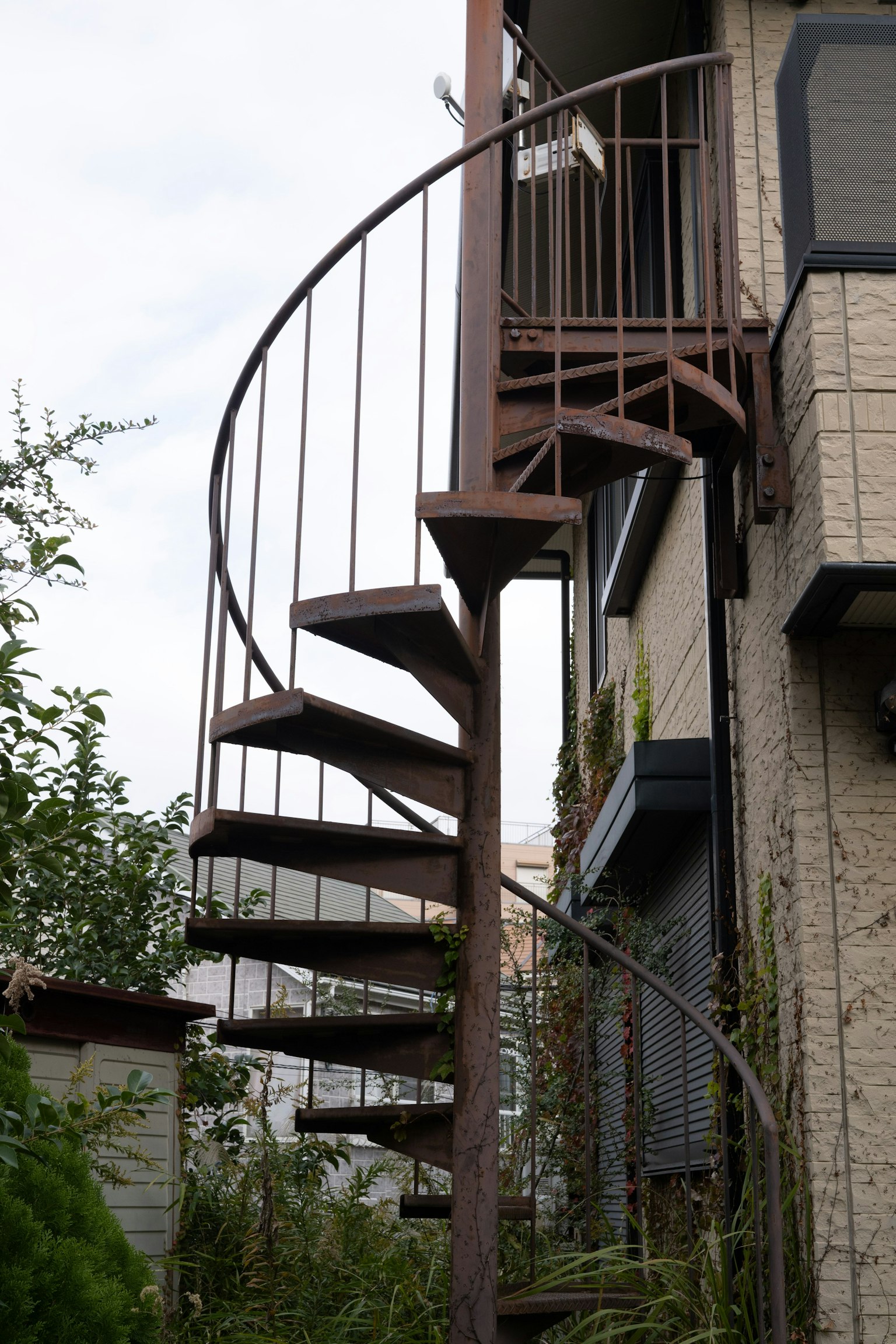 Escalier en colimaçon attaché à une maison entourée de verdure