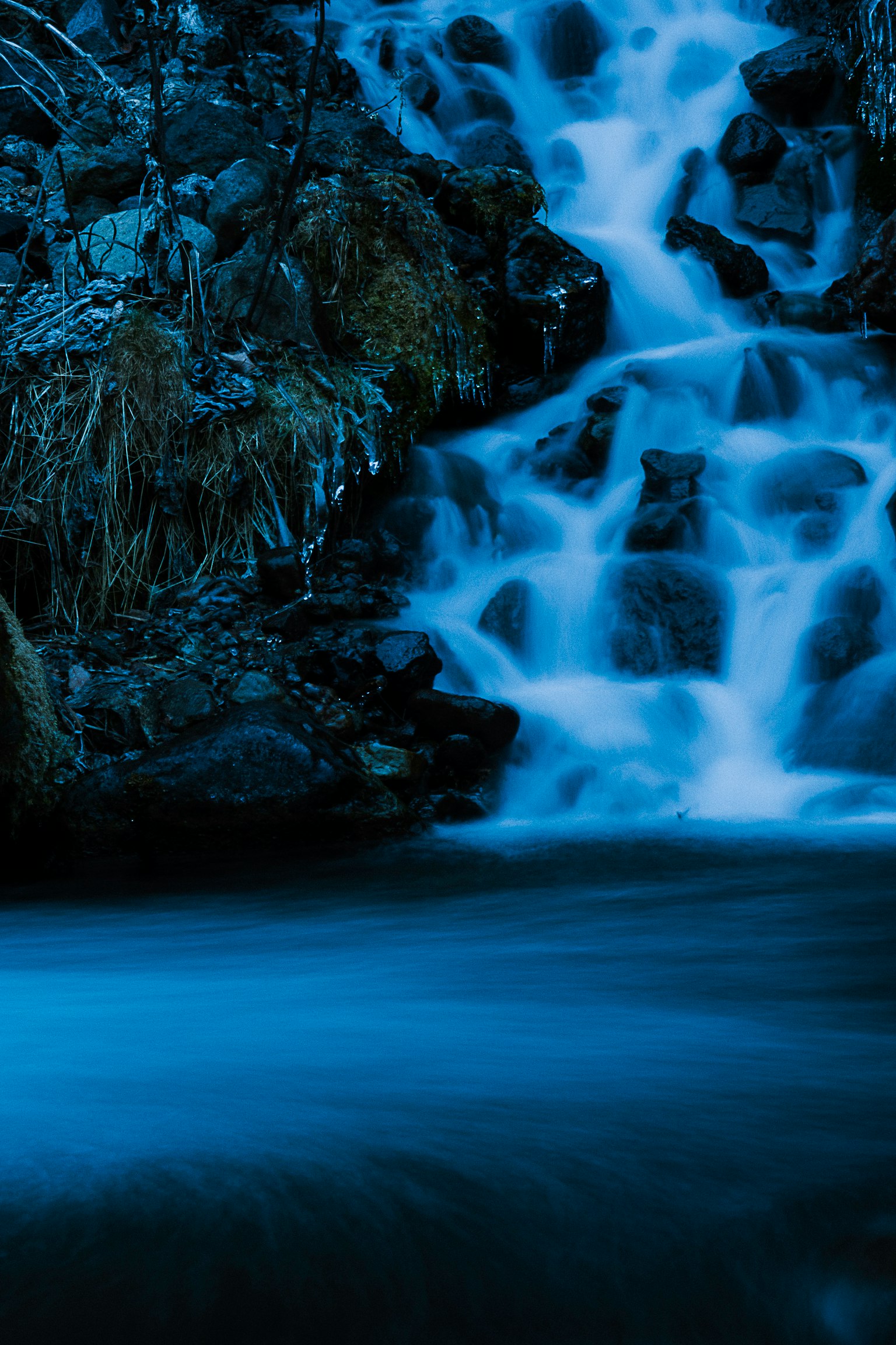 Chute d'eau bleue se déversant sur des rochers avec une surface d'eau calme