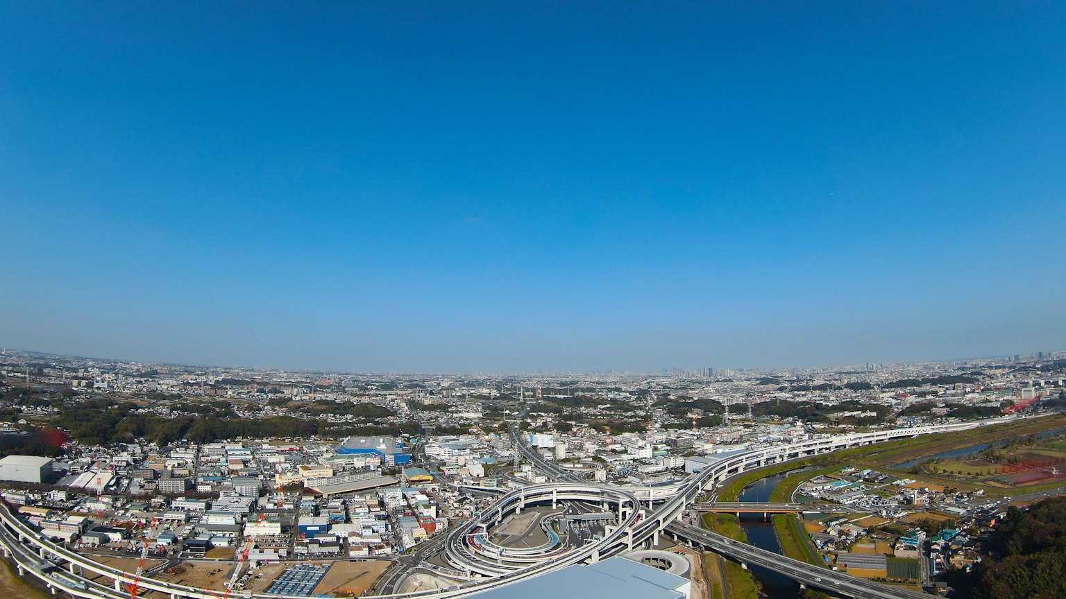 ทิวทัศน์แบบพาโนรามาของเมืองใต้ท้องฟ้าสีฟ้า มีบ้านและถนน