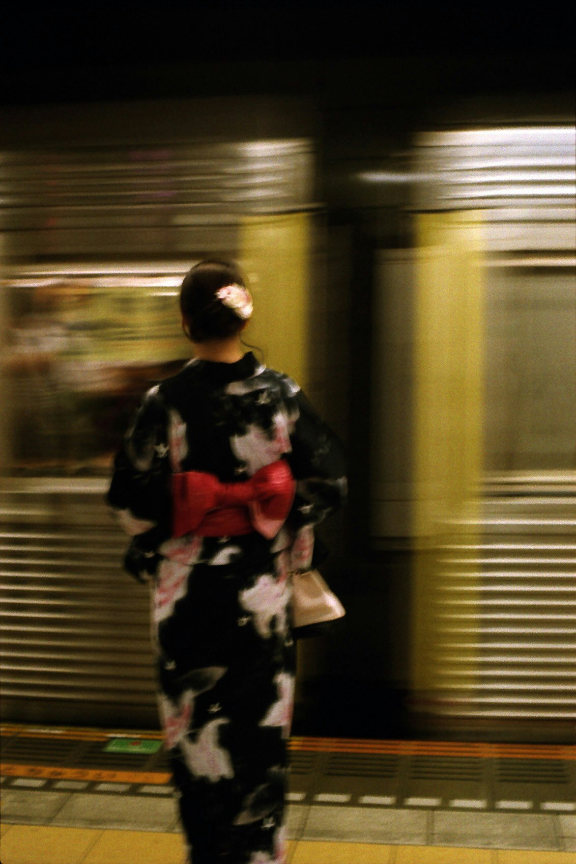 夜の駅で子どもを抱く人物の後ろ姿