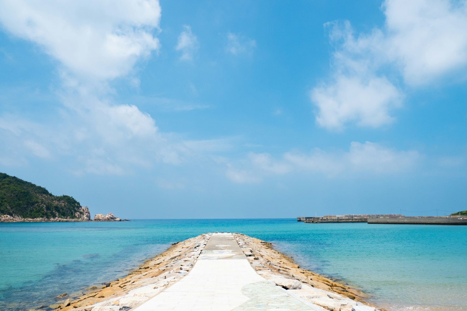 Hermoso paisaje costero con mar y cielo azules Un camino blanco que lleva al agua