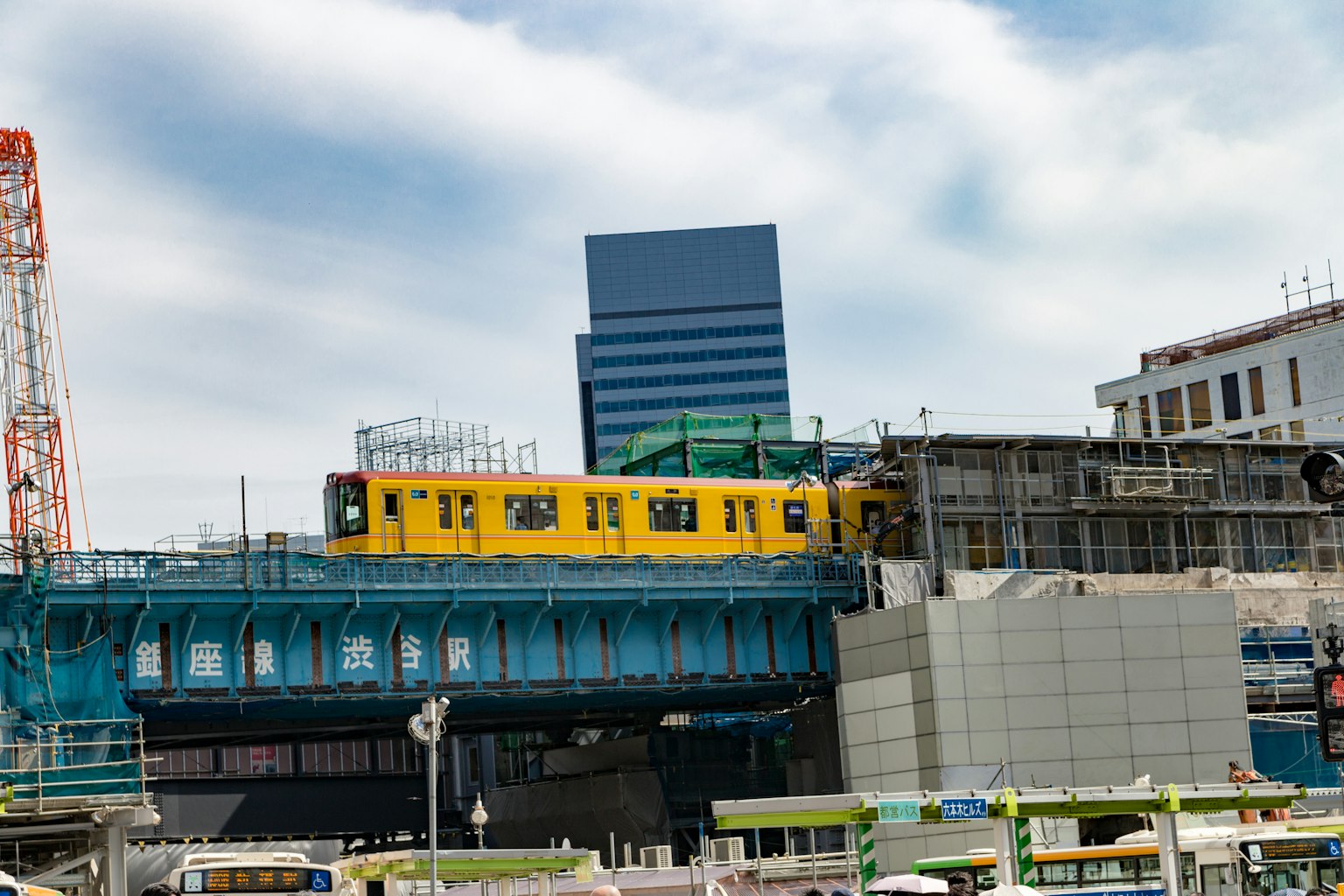 Yellow train passing in front of a new building under construction