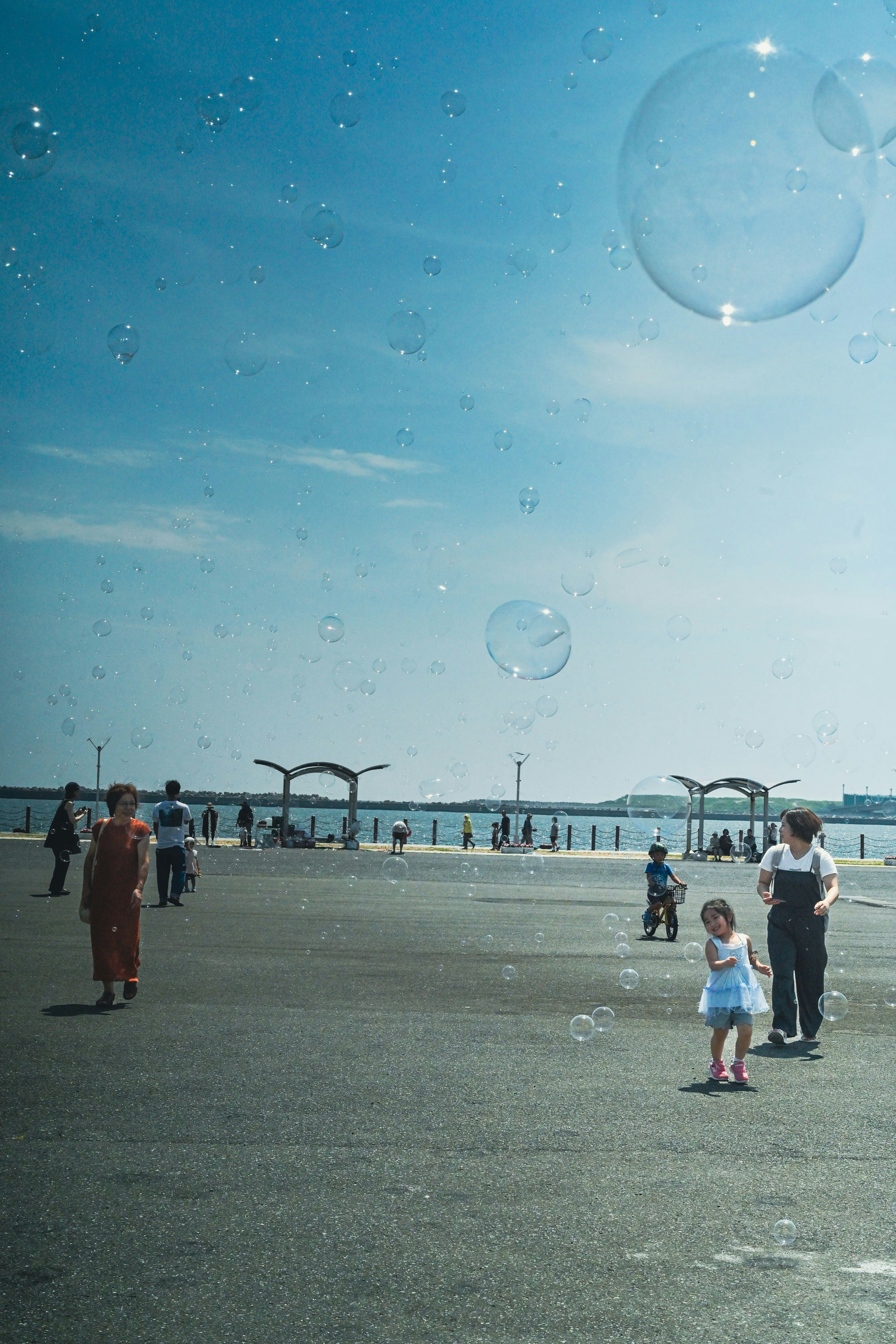 浜辺でシャボン玉を追いかける子どもと家族の夏の風景