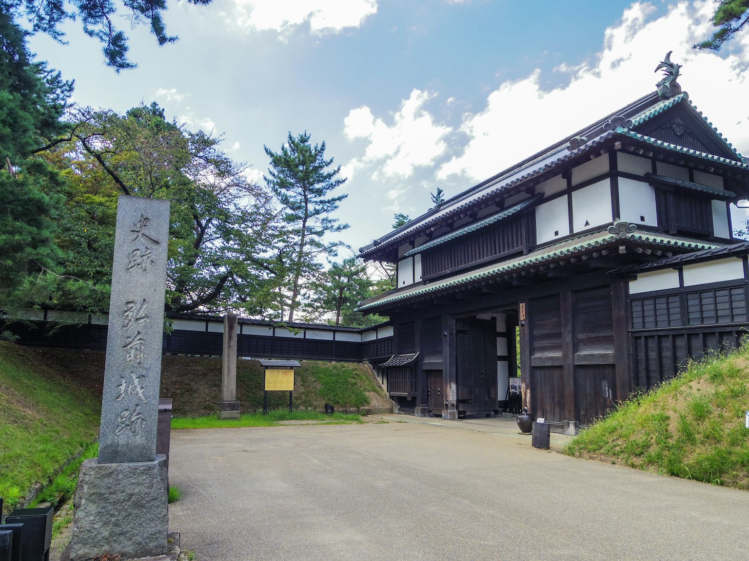 Bâtiment japonais traditionnel avec un marqueur en pierre et des arbres environnants