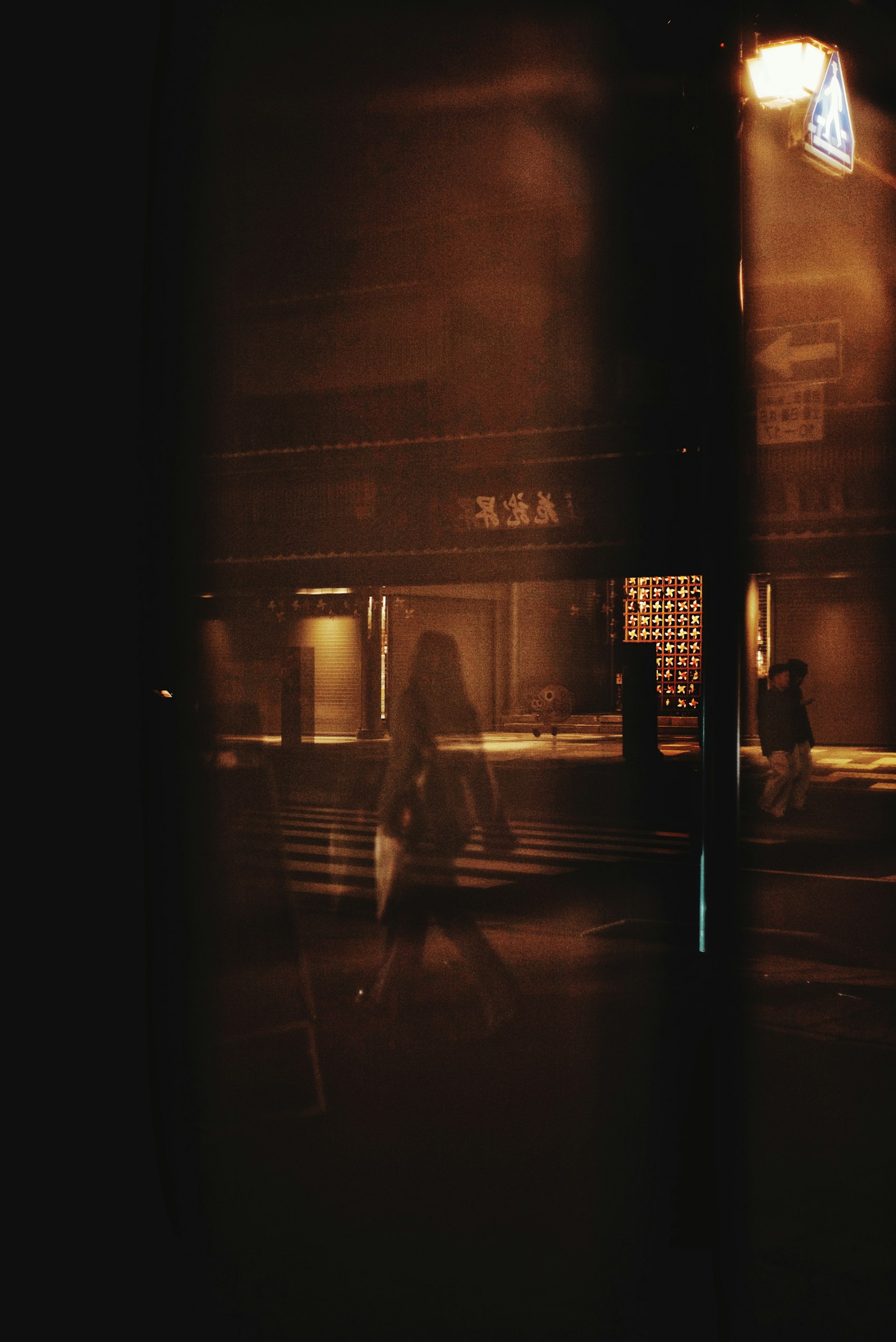 Silhouette d'une personne marchant dans une rue sombre avec des reflets de lumière chaude