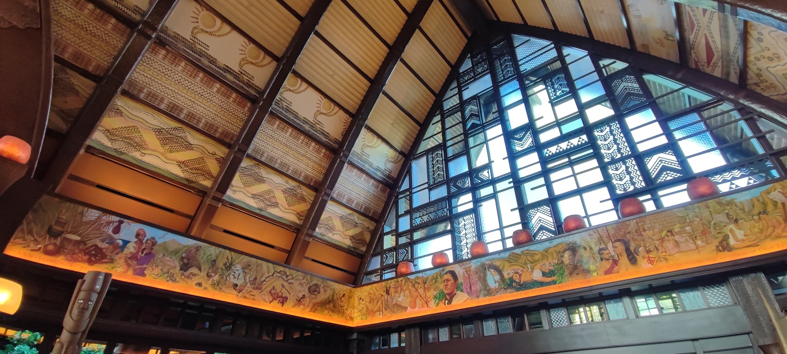 Interior of a building with a high ceiling decorative murals and large windows
