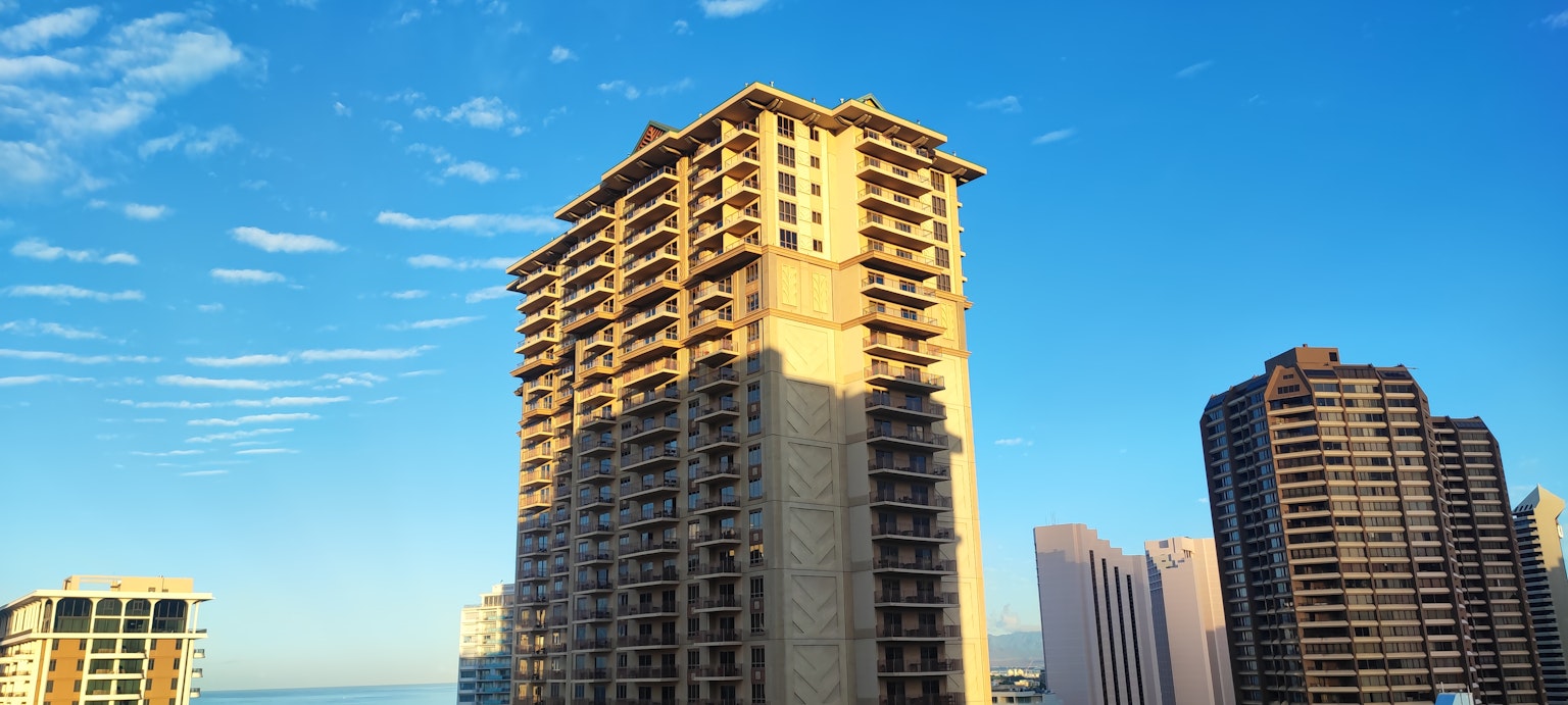 Vista de un edificio alto contra un cielo azul con sombras proyectadas