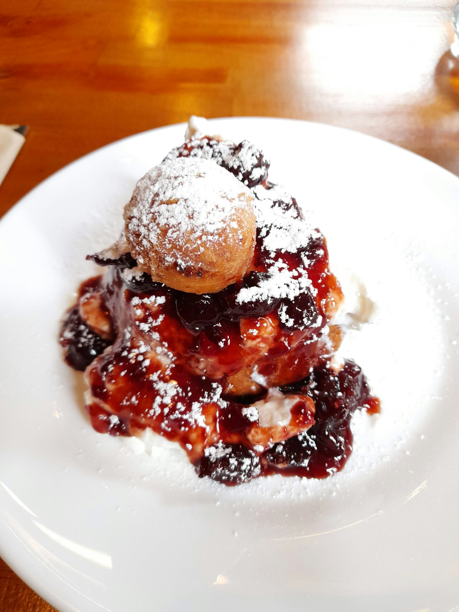 Sweet dessert topped with powdered sugar and berry sauce with a scoop of ice cream
