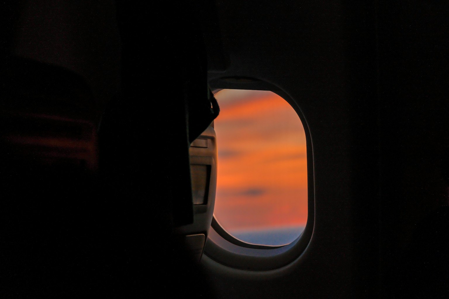 飛行機の窓から見える夕焼けの景色と暗いシルエット