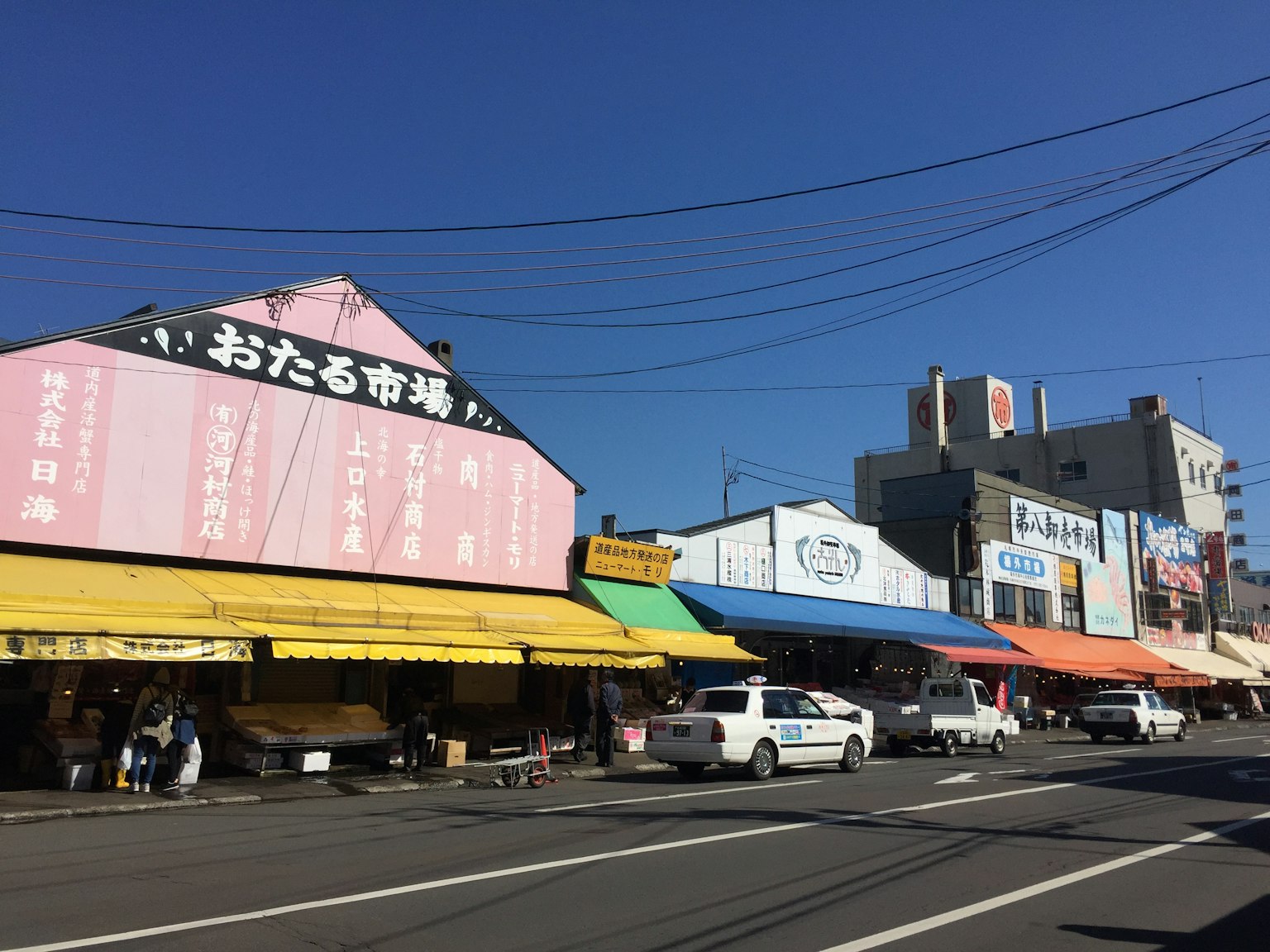 藍天下排列著色彩繽紛的攤位和商店的街道