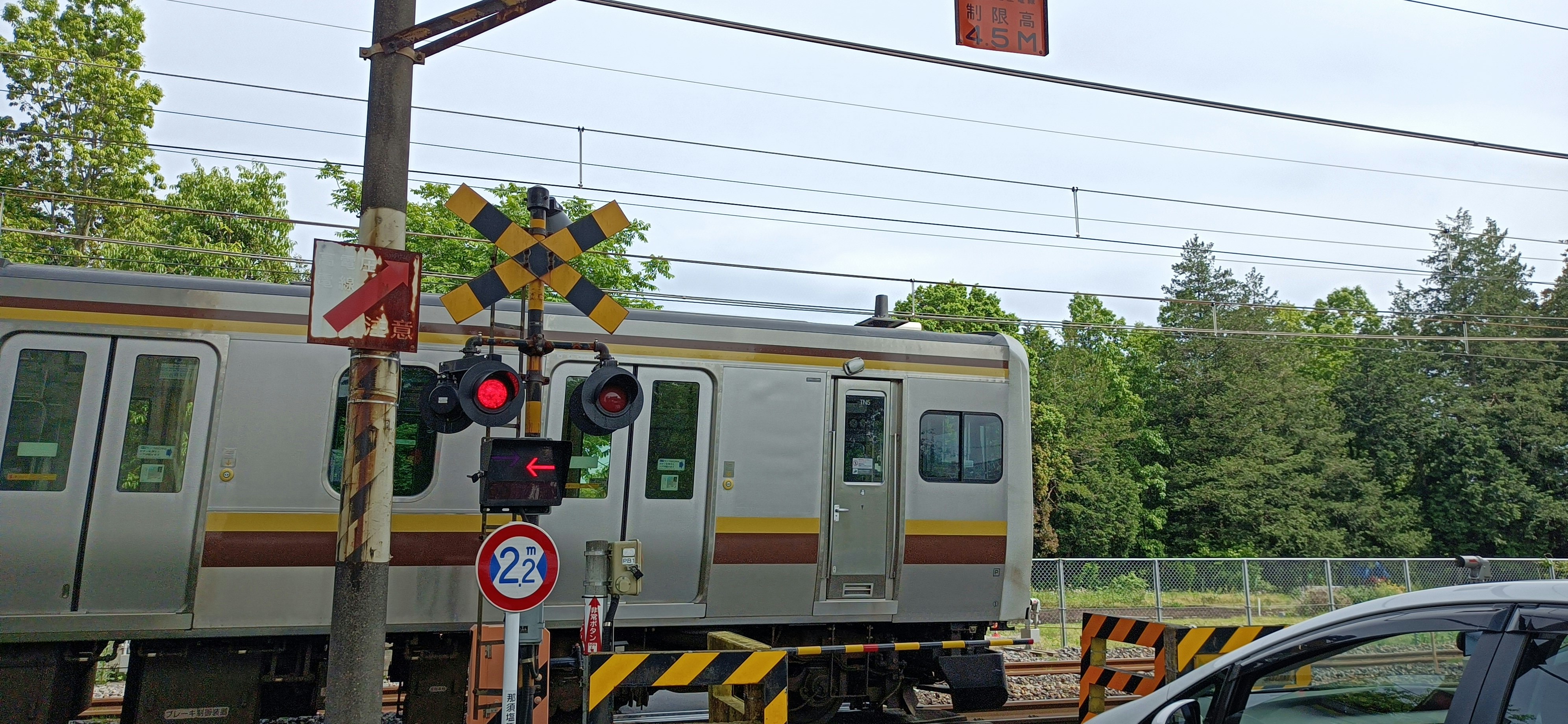 踏切の遮断機と電車が並ぶ線路風景