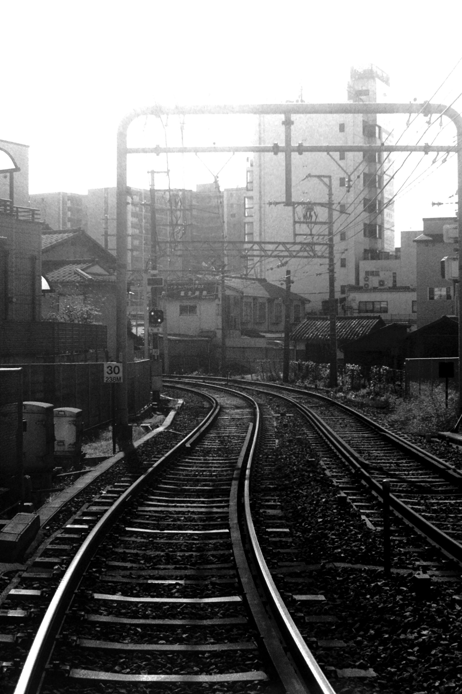 รางรถไฟโค้งในทิวทัศน์เมืองขาวดำ