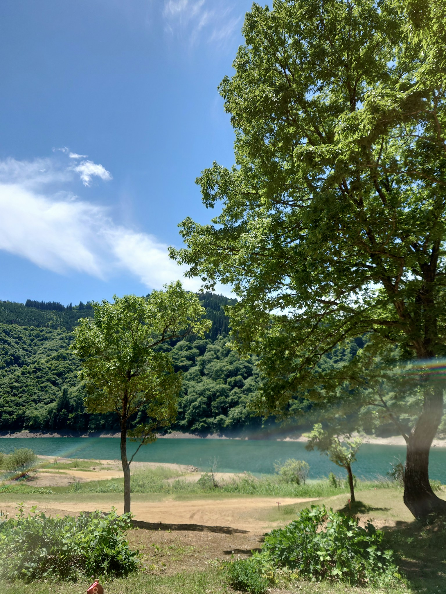 湖泊的風景，周圍是綠色的樹木和藍天
