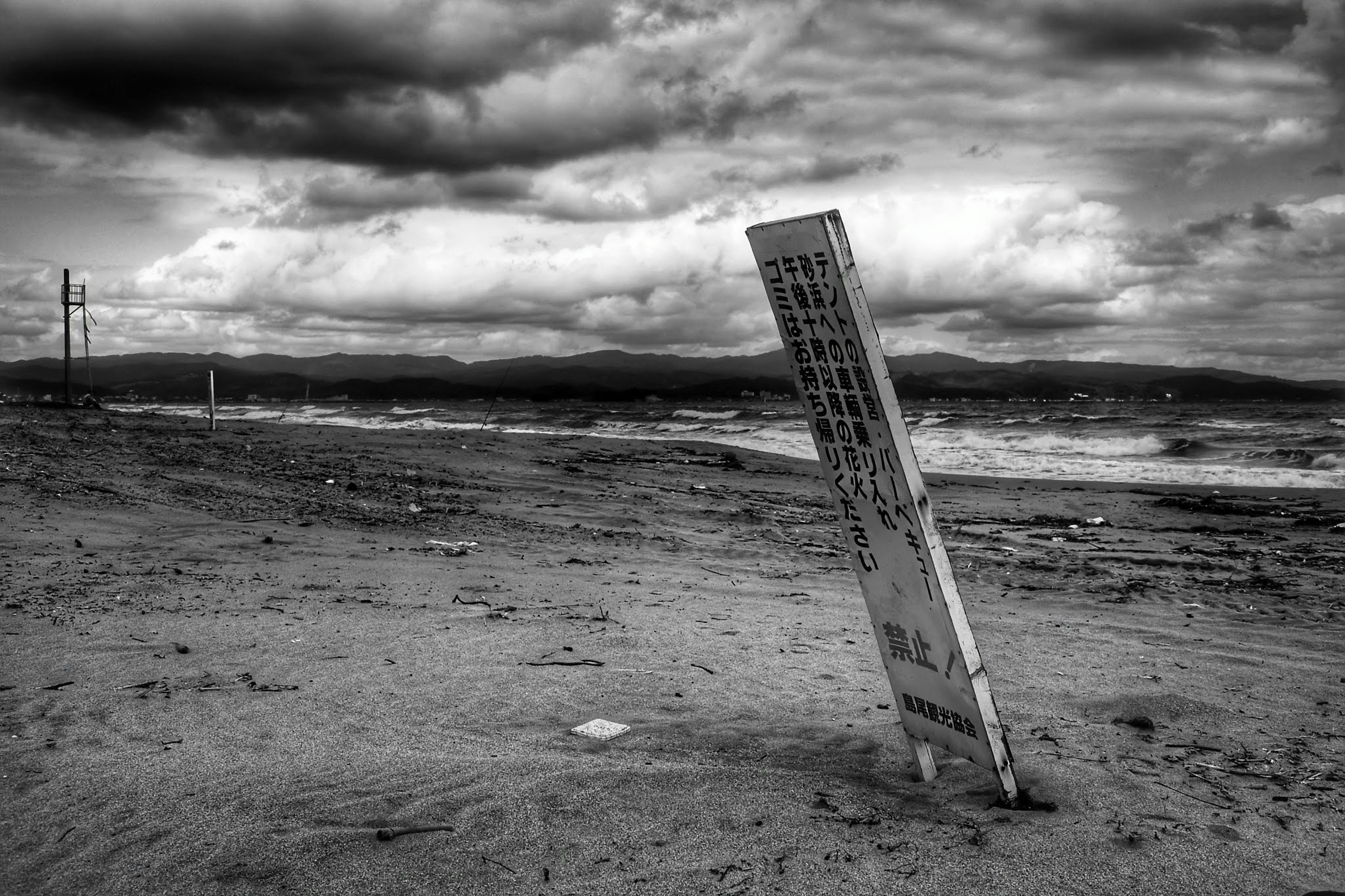 Cartello rovesciato sulla sabbia in spiaggia in bianco e nero