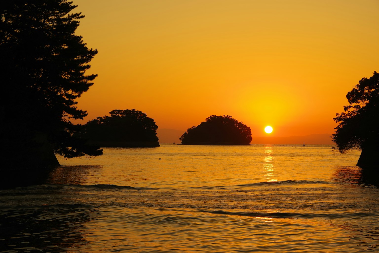 Ein wunderschöner Sonnenuntergang über dem Meer mit silhouettierten Inseln im Hintergrund