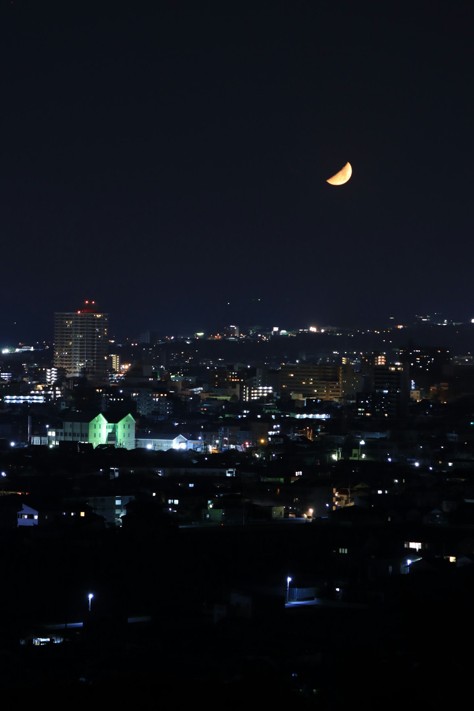 Garis langit kota di malam hari dengan bulan sabit di atas