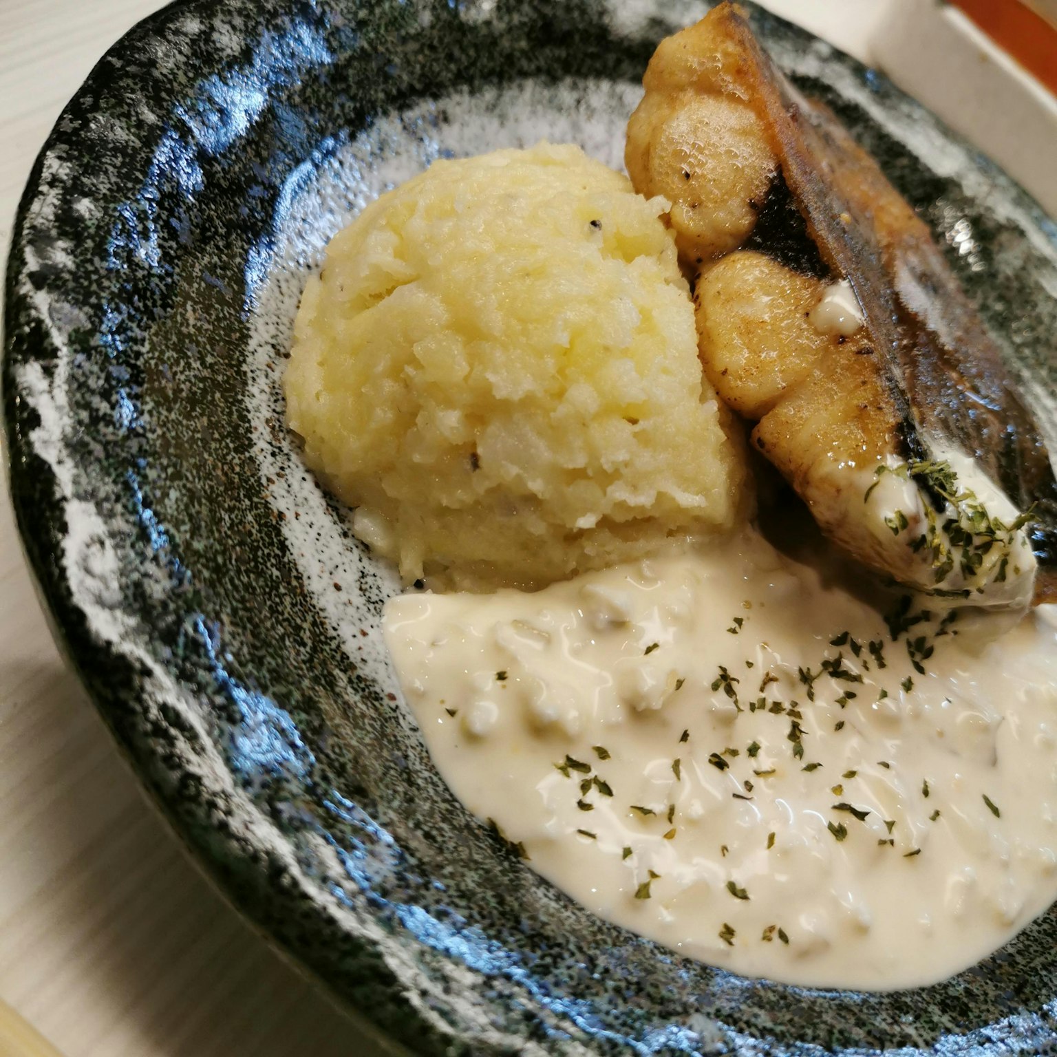 黑色盘子里盛着鱼肉和米饭的奶油酱