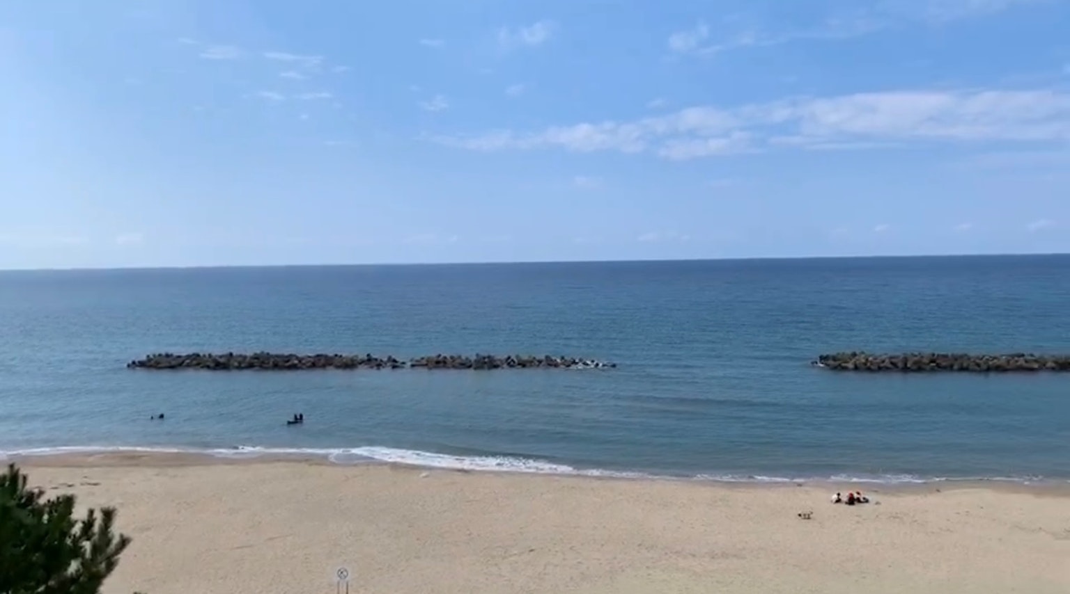 Una escena de playa con océano azul y cielo, arena y rompeolas