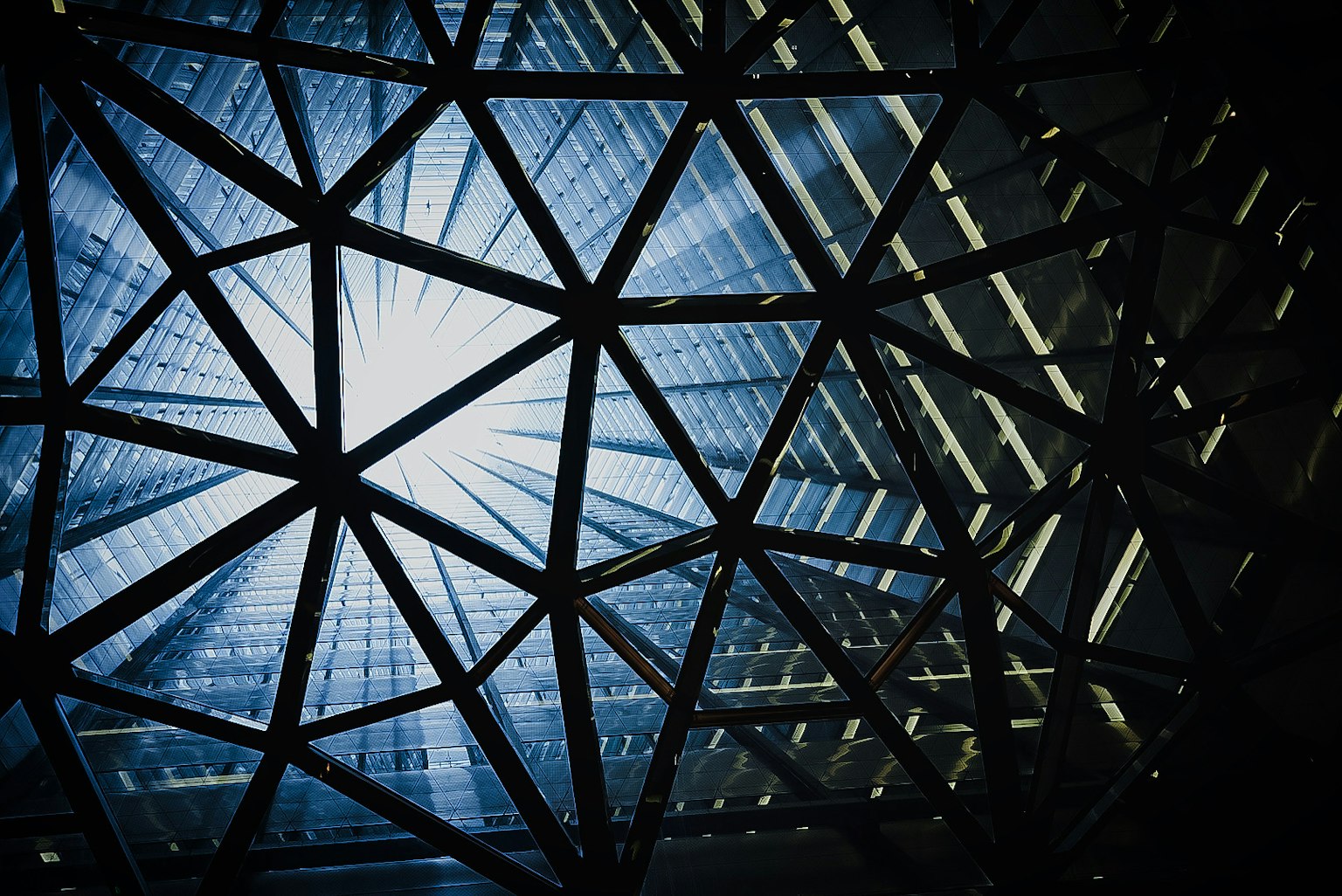 Geometric triangular design viewed from inside a glass building looking up