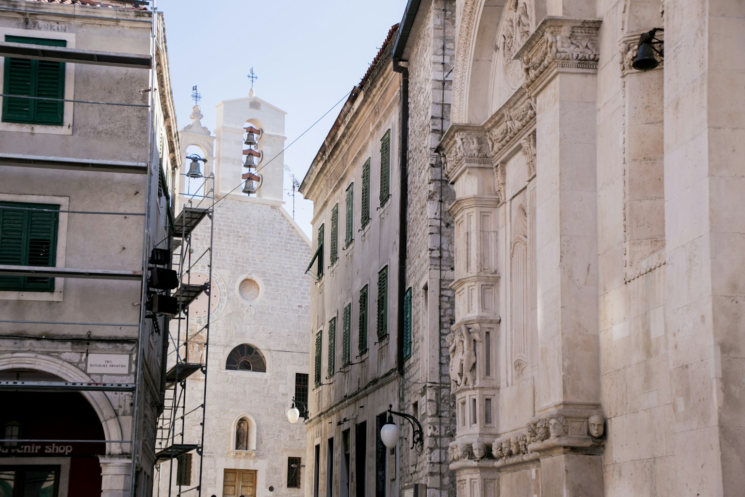 Vue d'une rue étroite avec des bâtiments anciens et un clocher blanc visible
