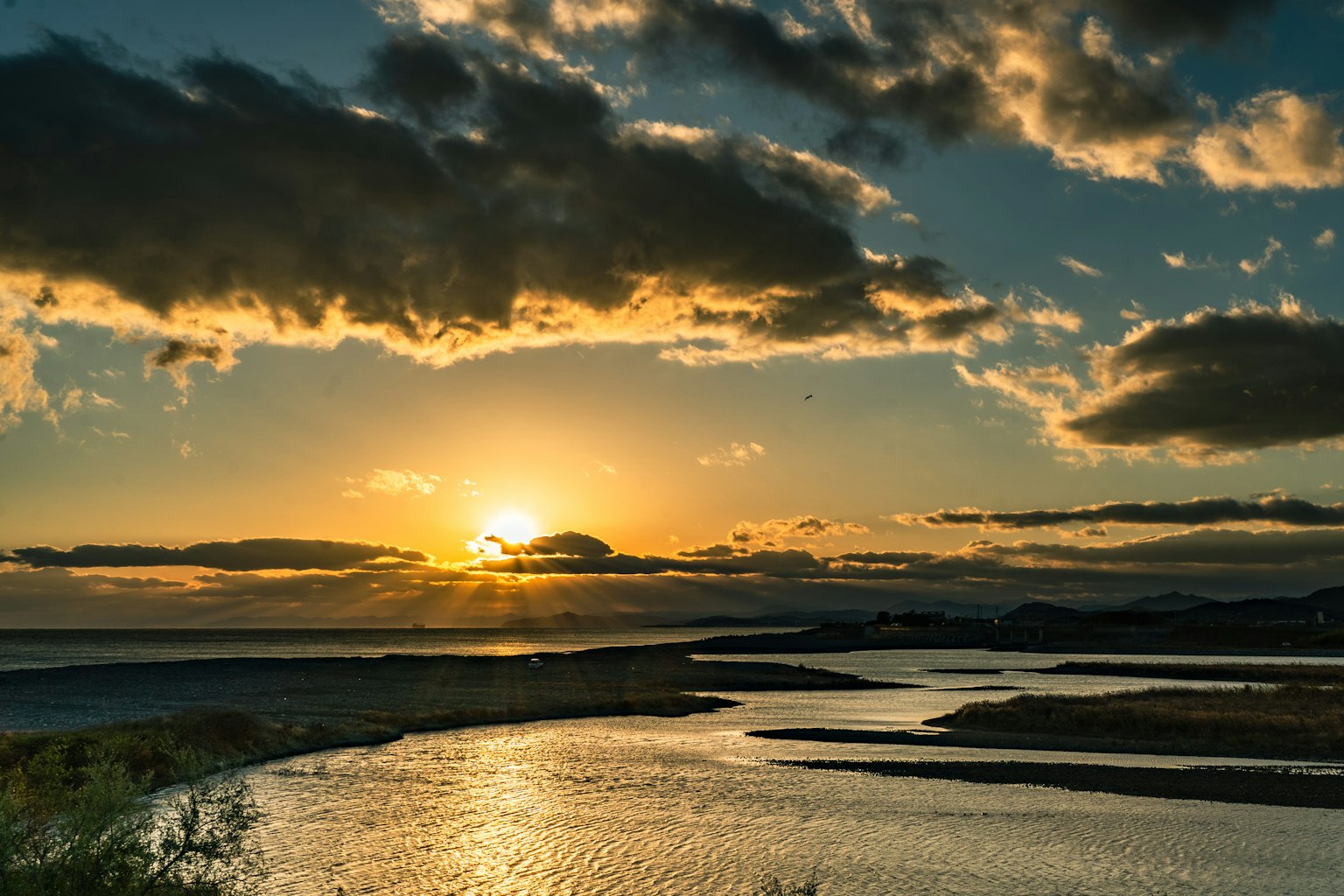 Coucher de soleil sur une rivière sinueuse avec des nuages dramatiques et des reflets sur l'eau