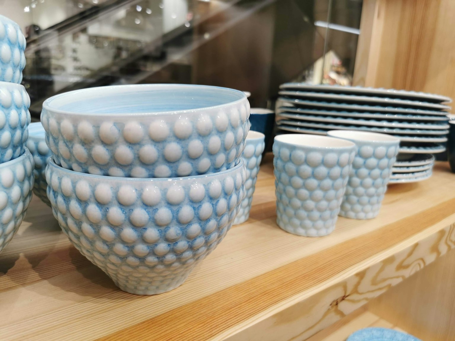 Des bols et des assiettes à pois bleus disposés sur une étagère en bois
