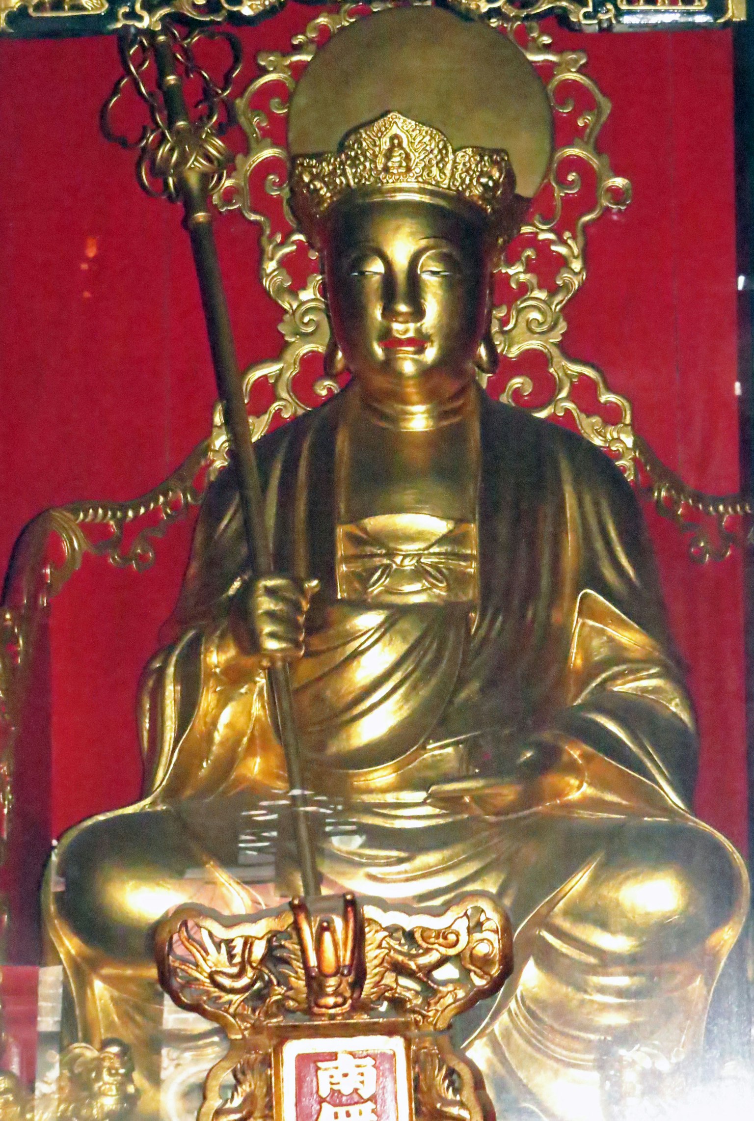 金色的神像坐在红色背景的宝座上