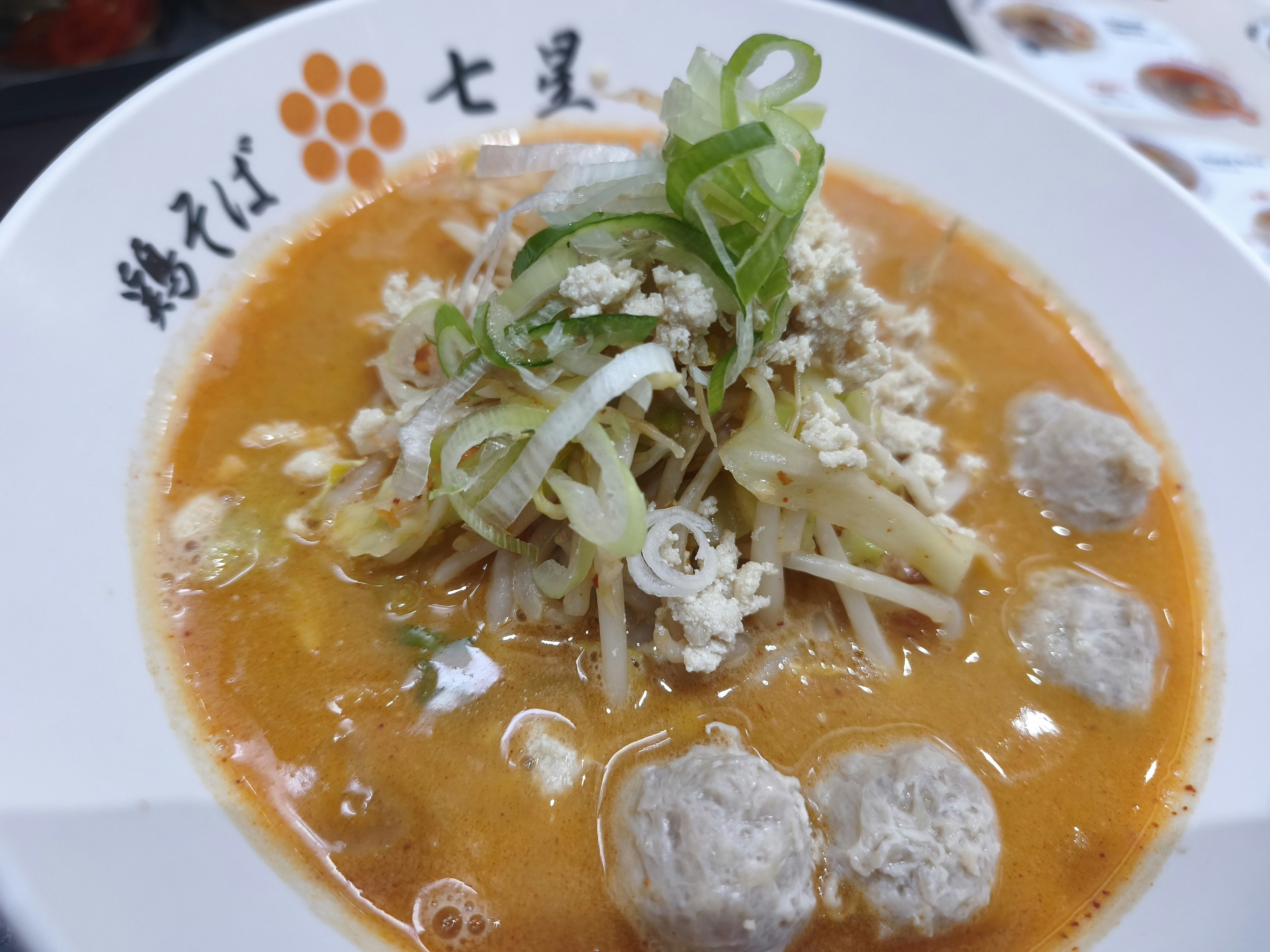 オレンジ色のスープに具材とネギがのったラーメン