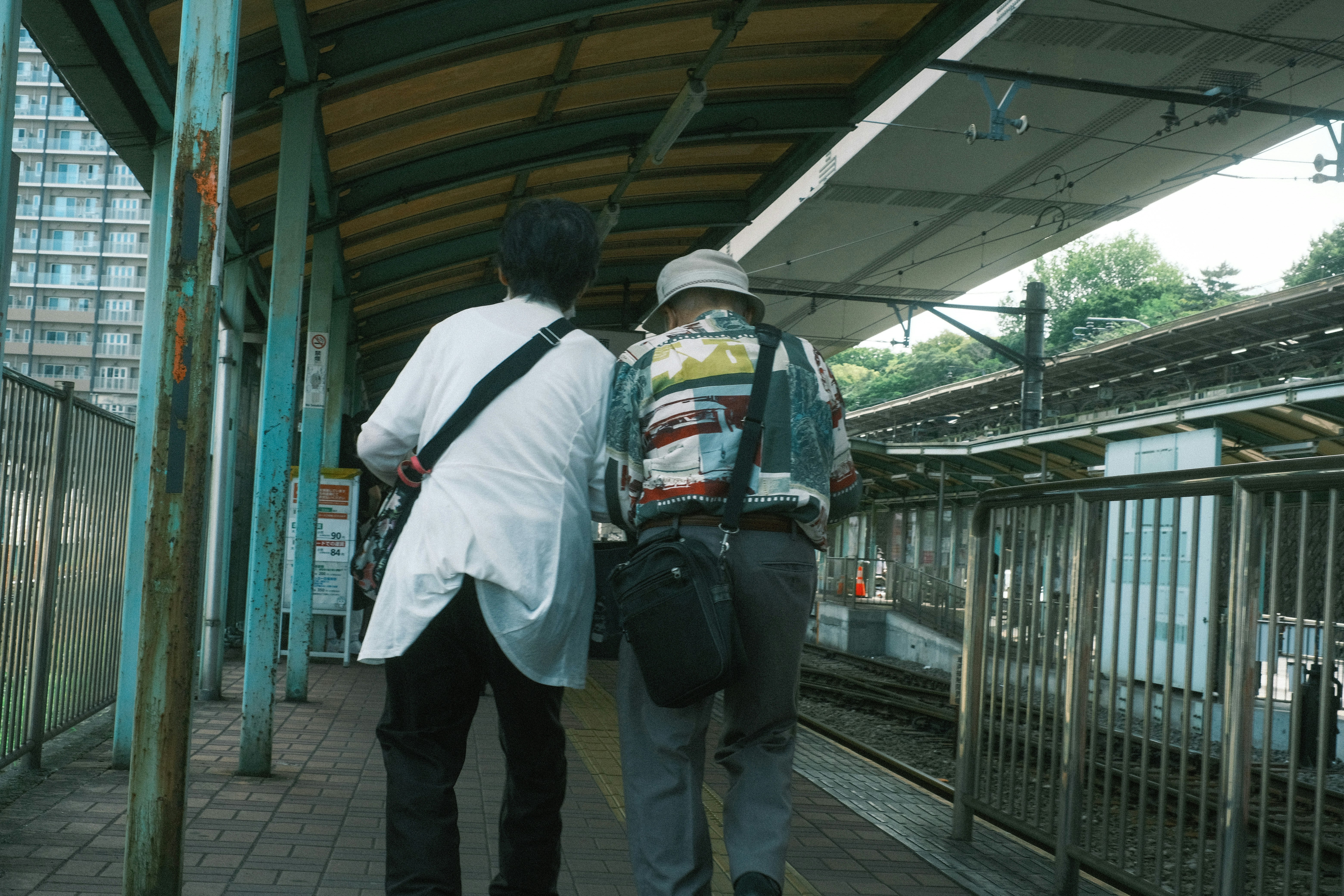 駅のホームで背中を向けて歩く人と荷物のある通勤風景