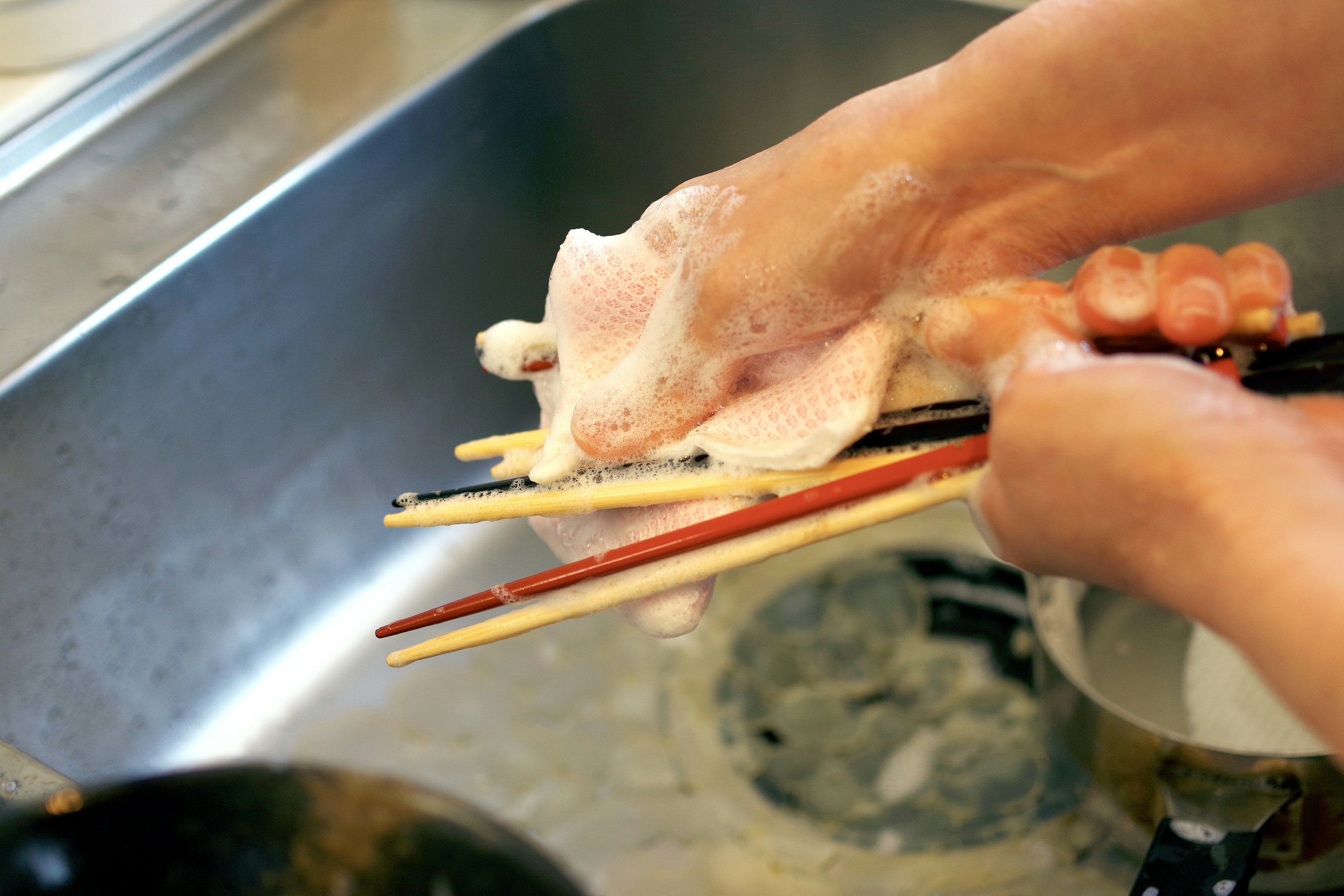 tay sơ chế thịt gà bằng đũa trong bếp
