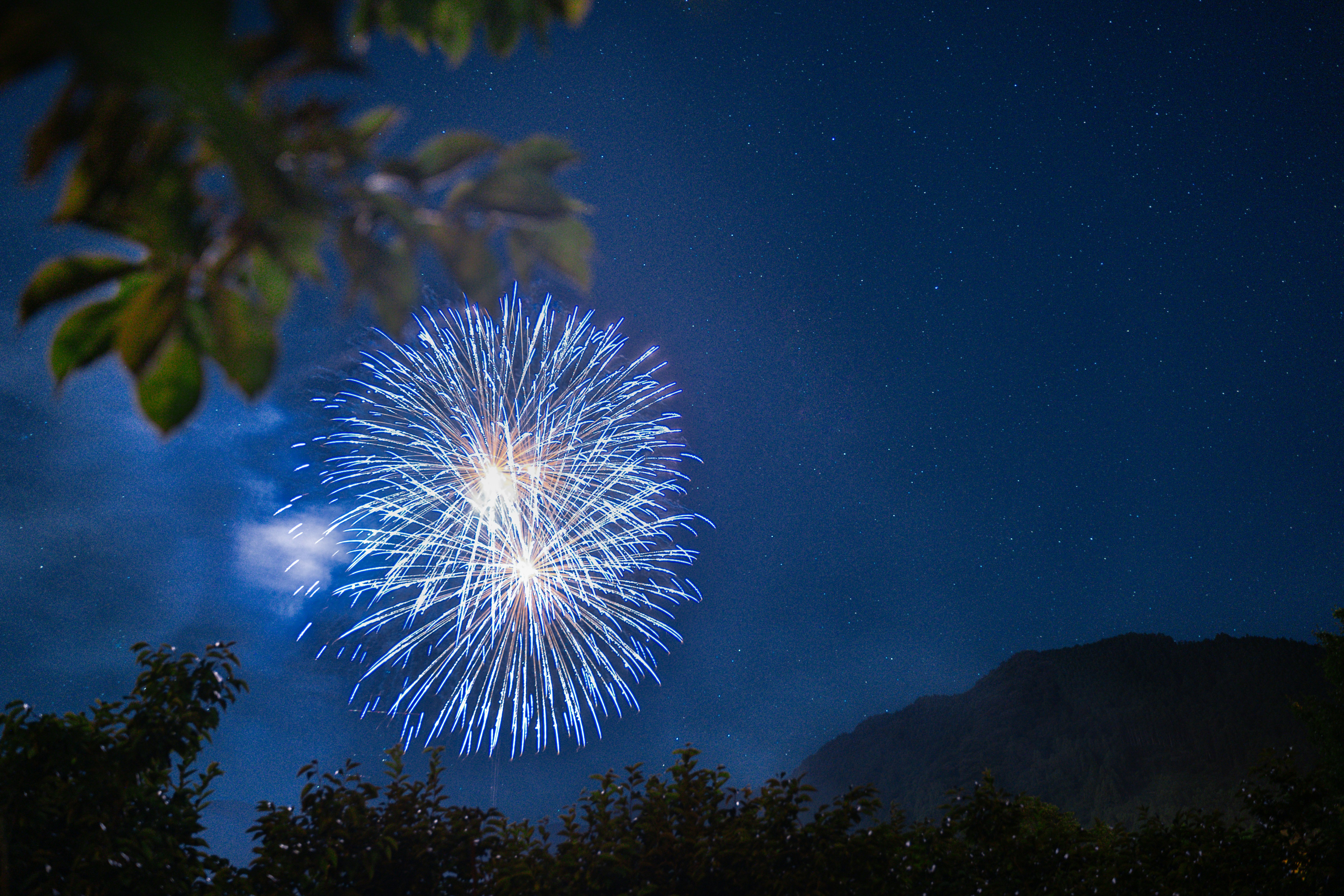 山並みを背景に夜空へ打ち上がる花火