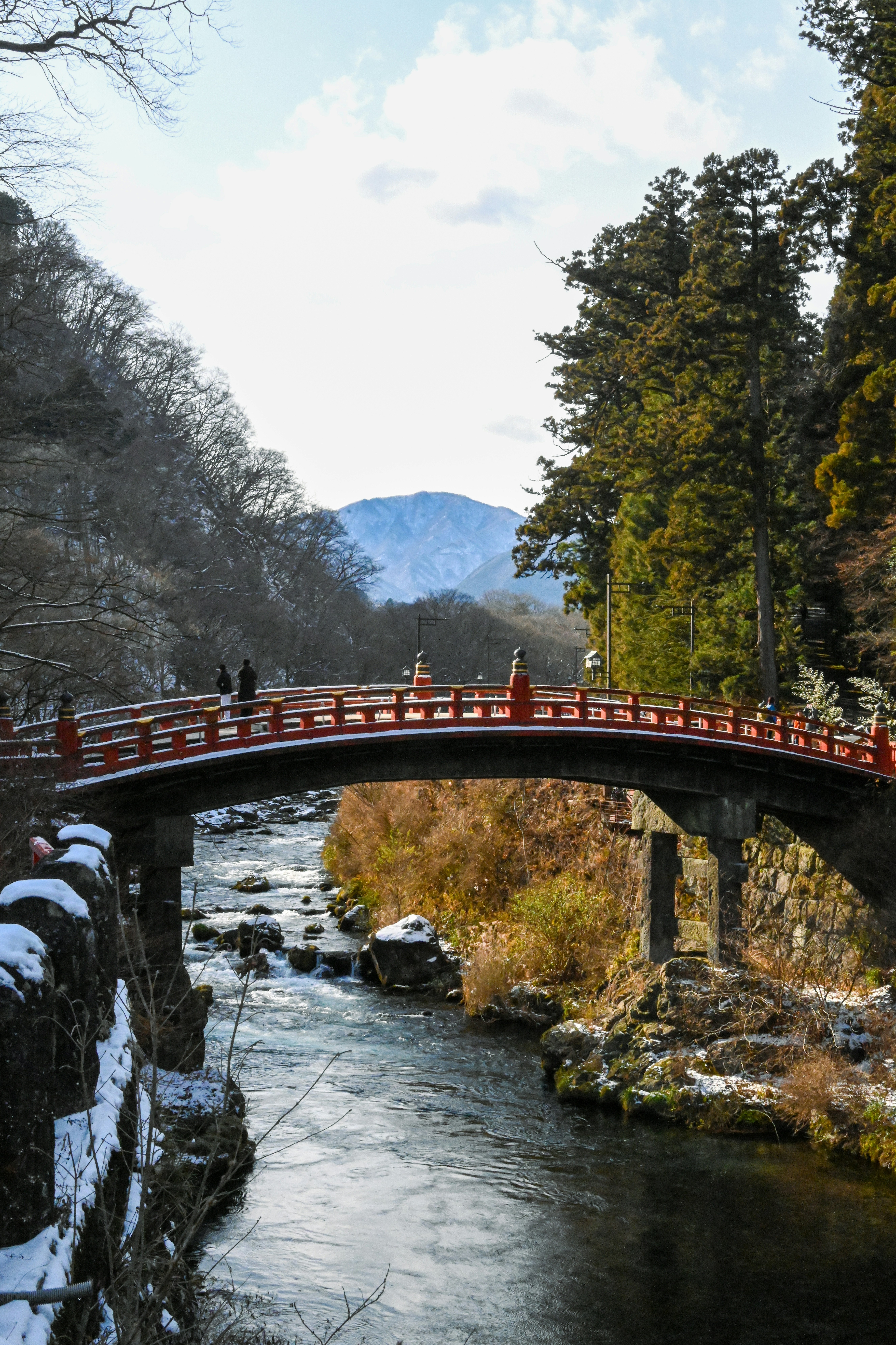 雪の神橋と赤いアーチの橋が川に架かる景色