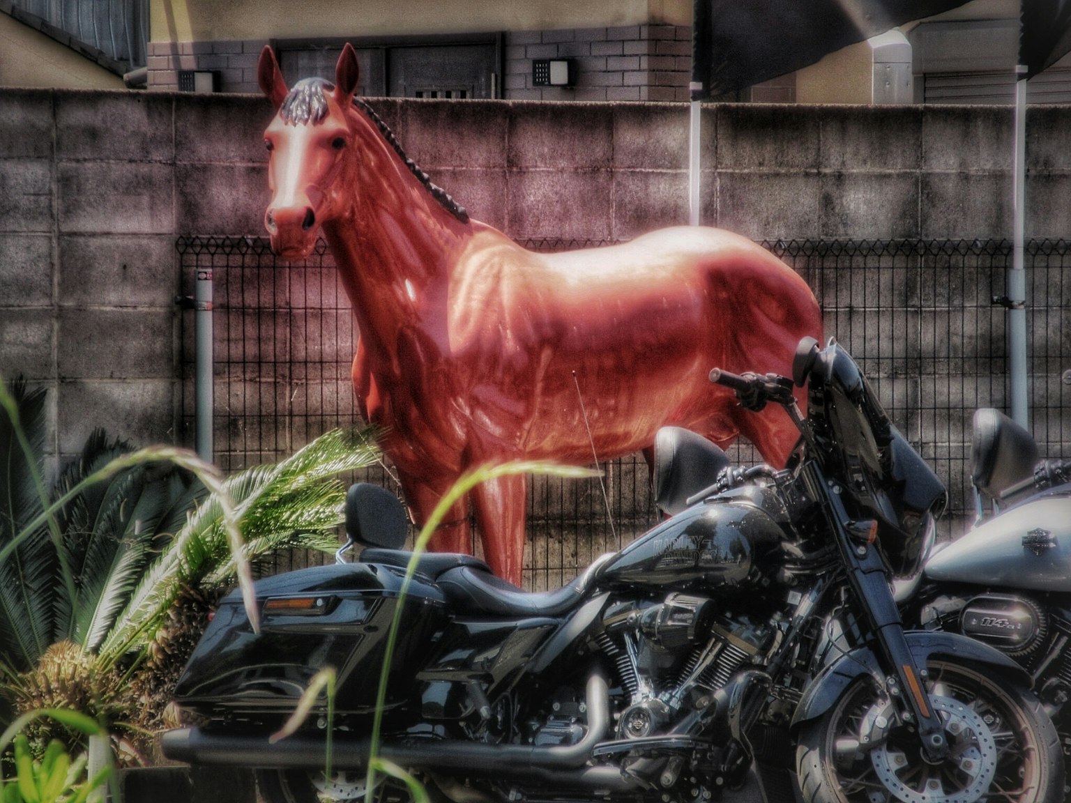 A red horse standing next to a black motorcycle