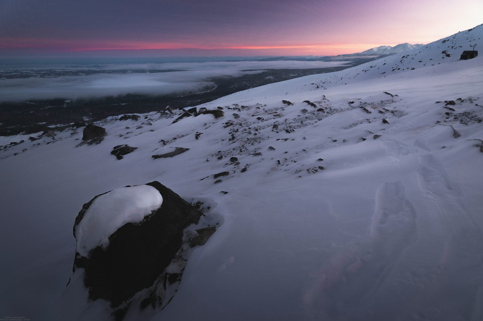 Rocher couvert de neige et paysage montagneux au crépuscule