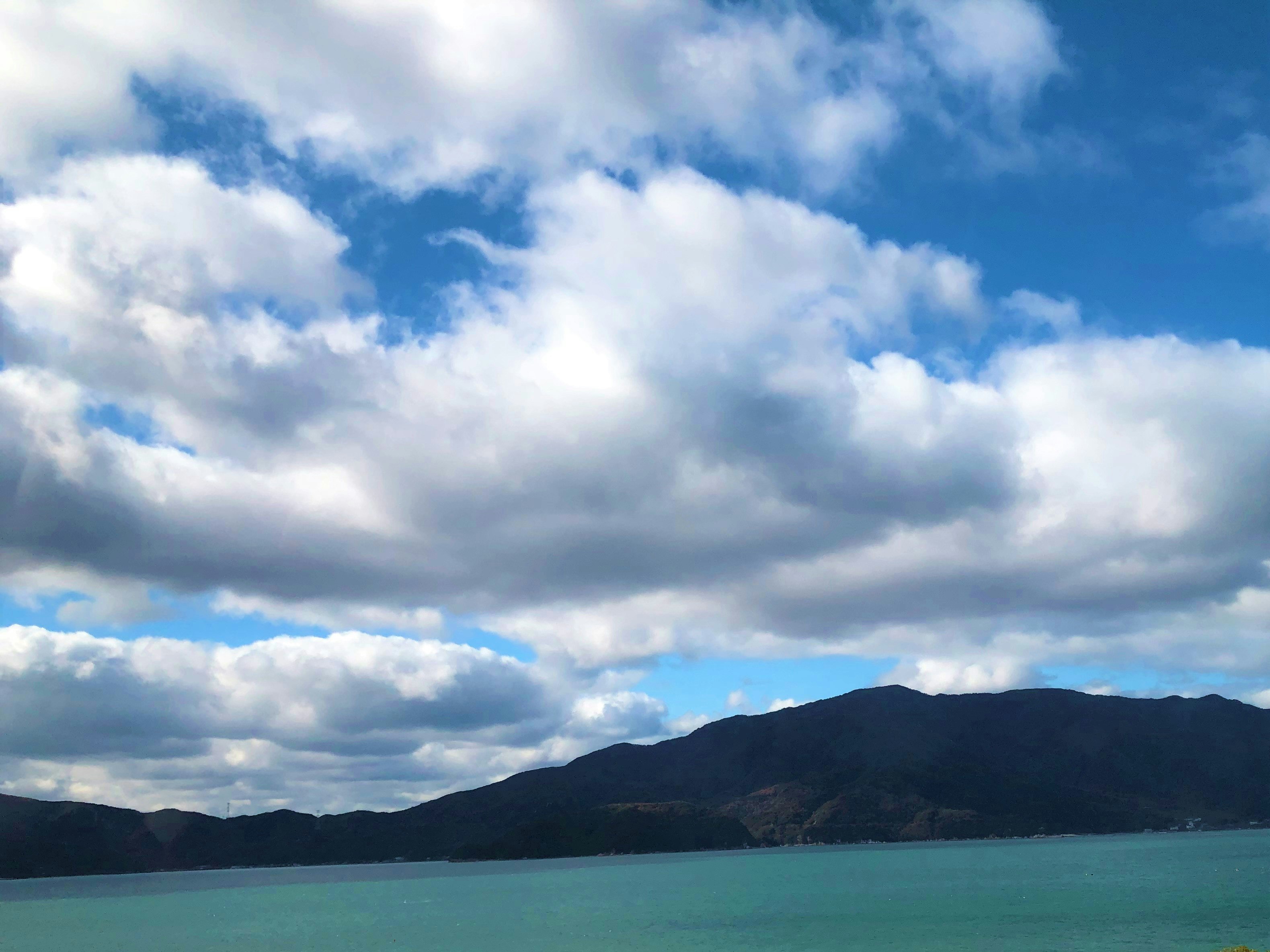 ターコイズ色の海と山並みを見渡す青空の風景