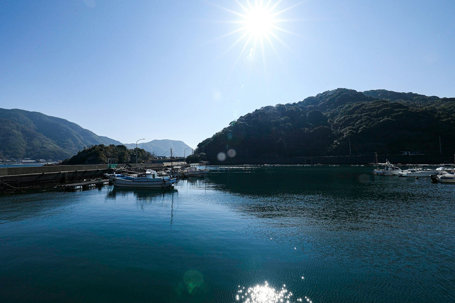 Mare calmo con barche e luce solare brillante che si riflette sull'acqua