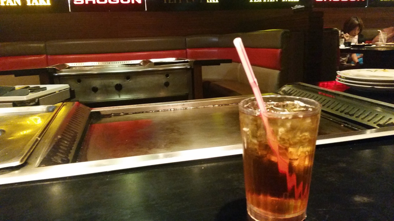 Interior de un restaurante con una bebida en el mostrador y una estación de parrilla