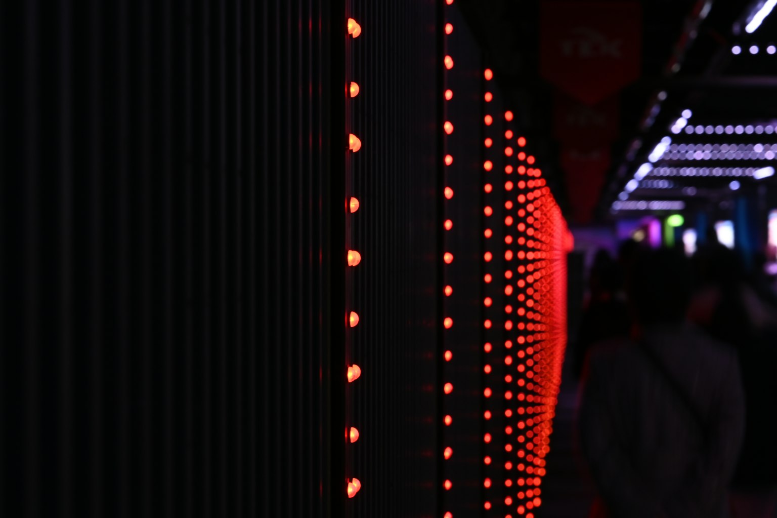 Close-up of a wall with blinking red lights people walking by