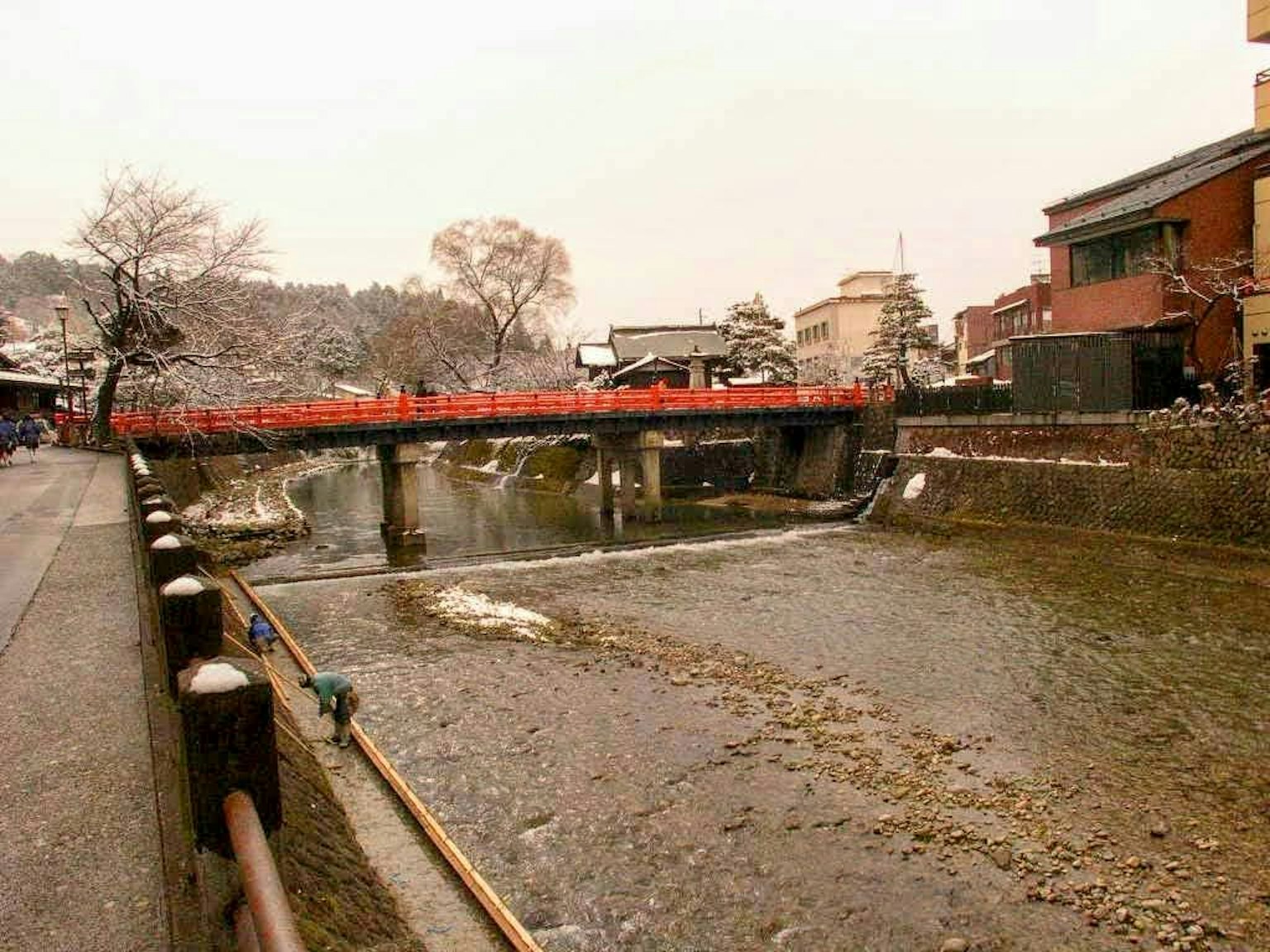 Vista invernale panoramica di un fiume con un ponte rosso