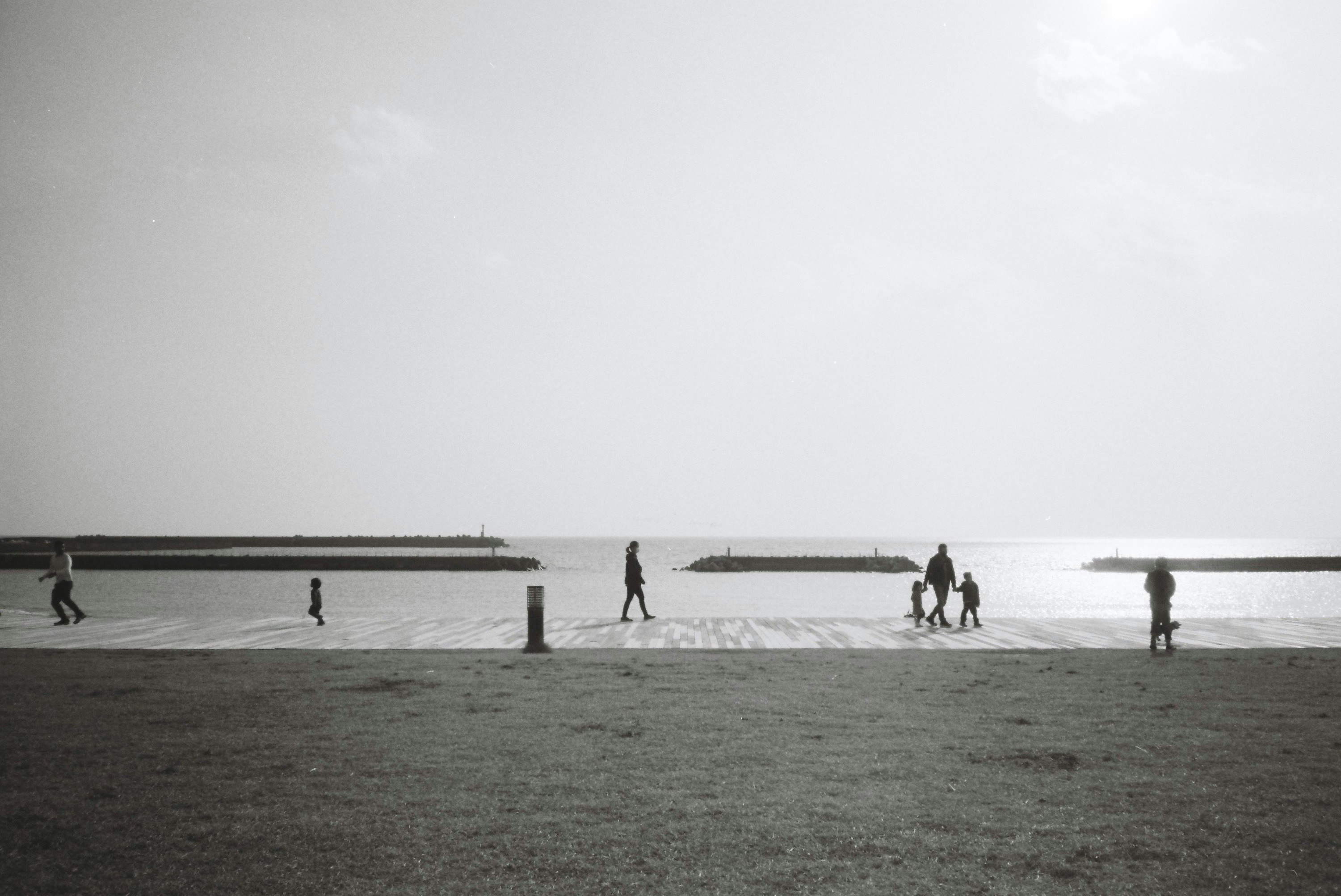 escena en monocromo de personas caminando por una amplia playa de arena