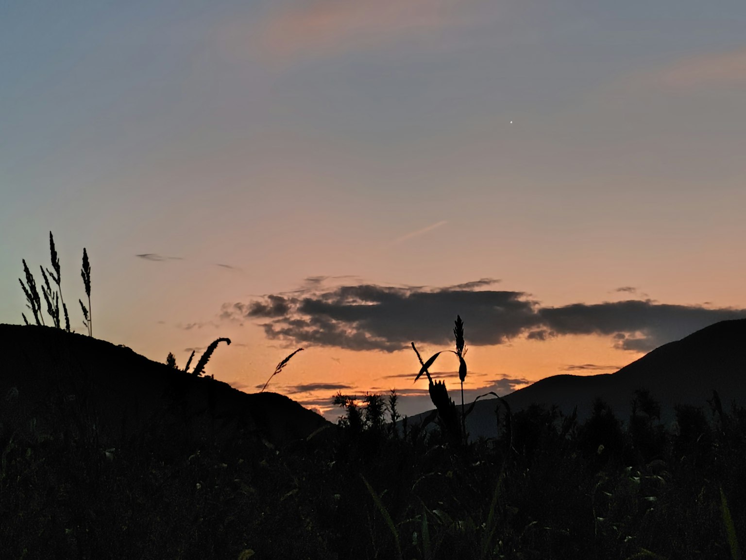 Silhouette de montagnes contre un ciel au coucher du soleil avec des nuages