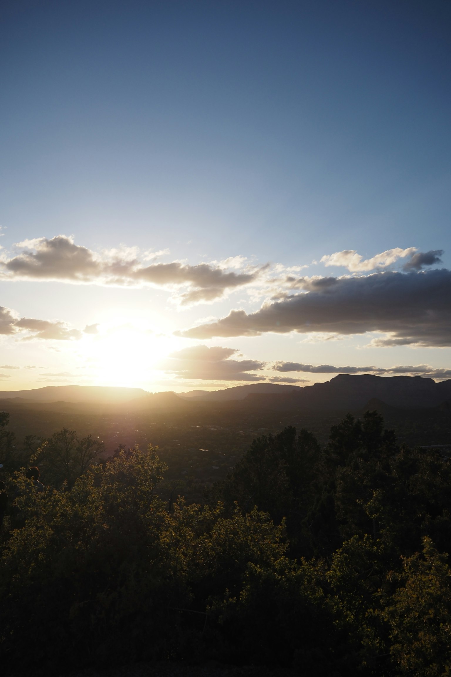 Tramonto sopra le montagne con vegetazione lussureggiante e cielo blu