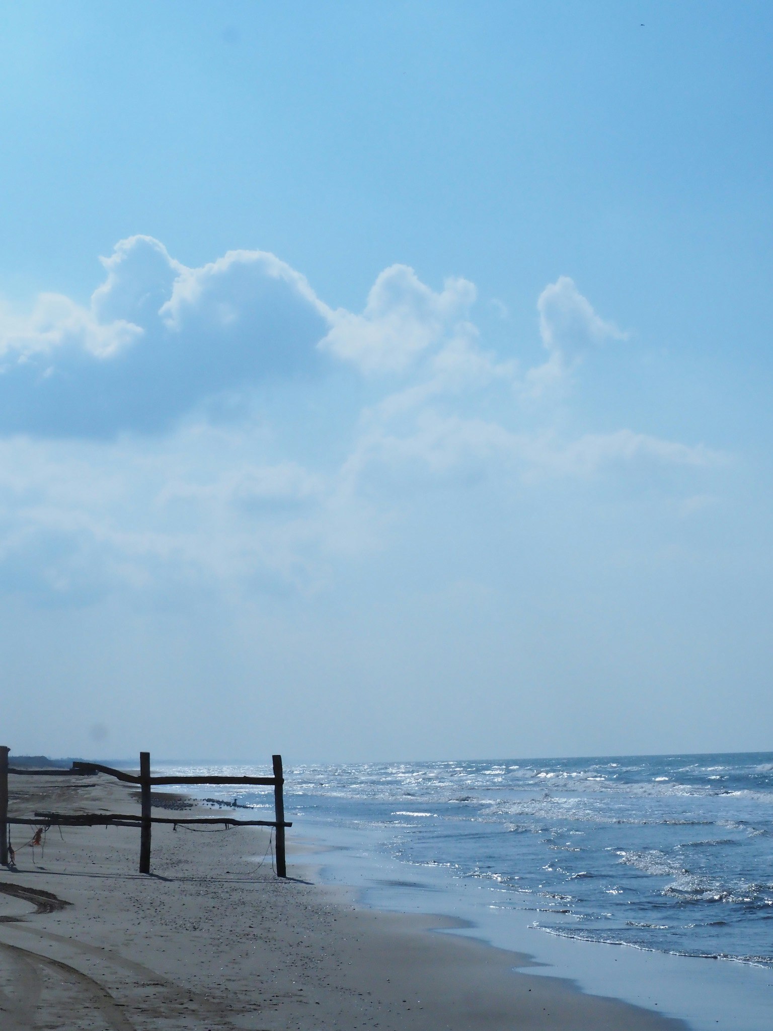 Blick auf blauen Himmel und Ozean mit Wellen am Strand entfernte Wolken am Himmel