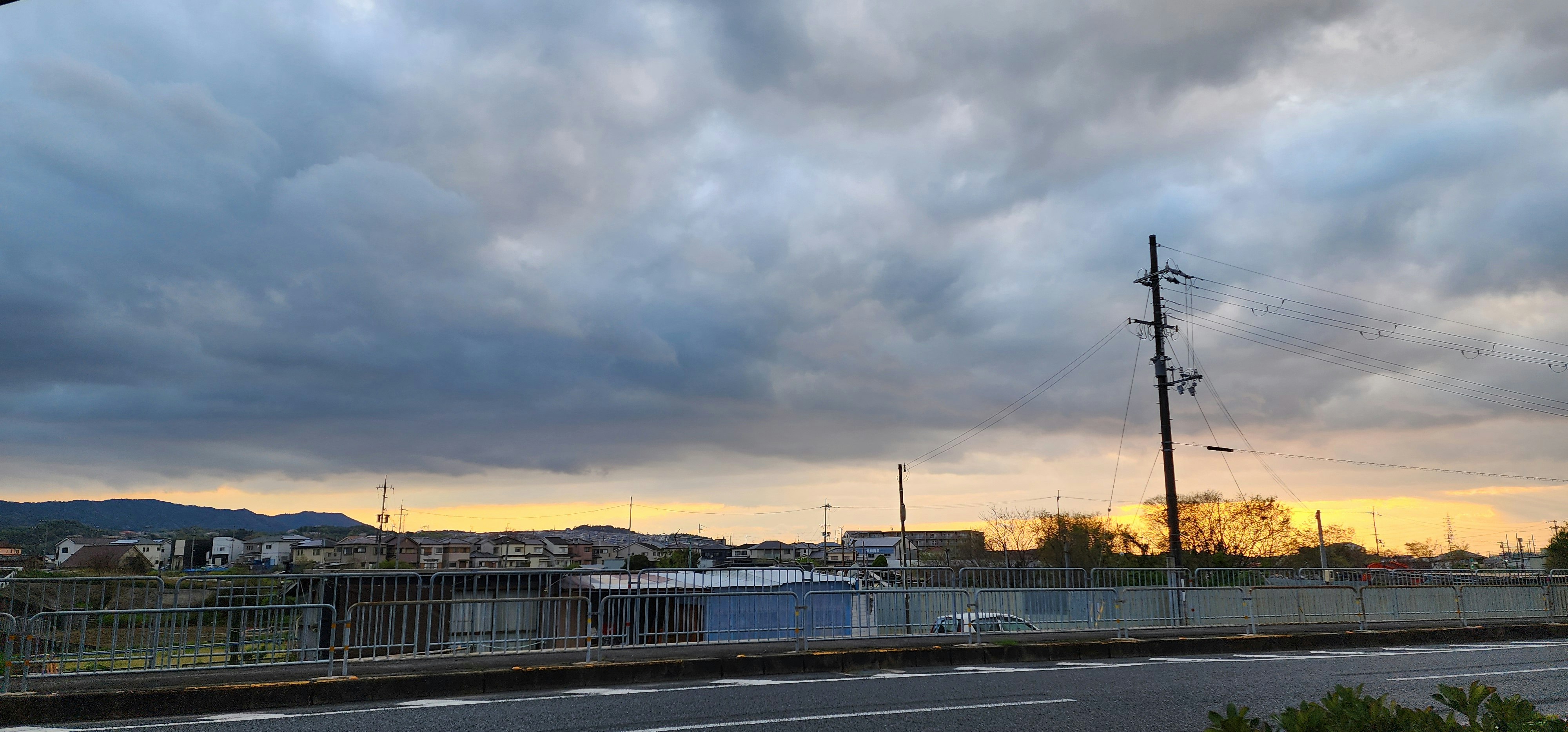 厚重云层下的天空与夕阳下的道路景