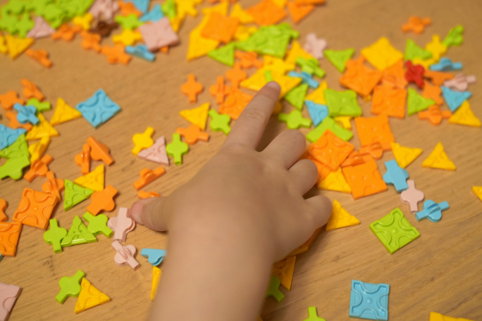 Colorful puzzle pieces scattered on a table with a hand pointing
