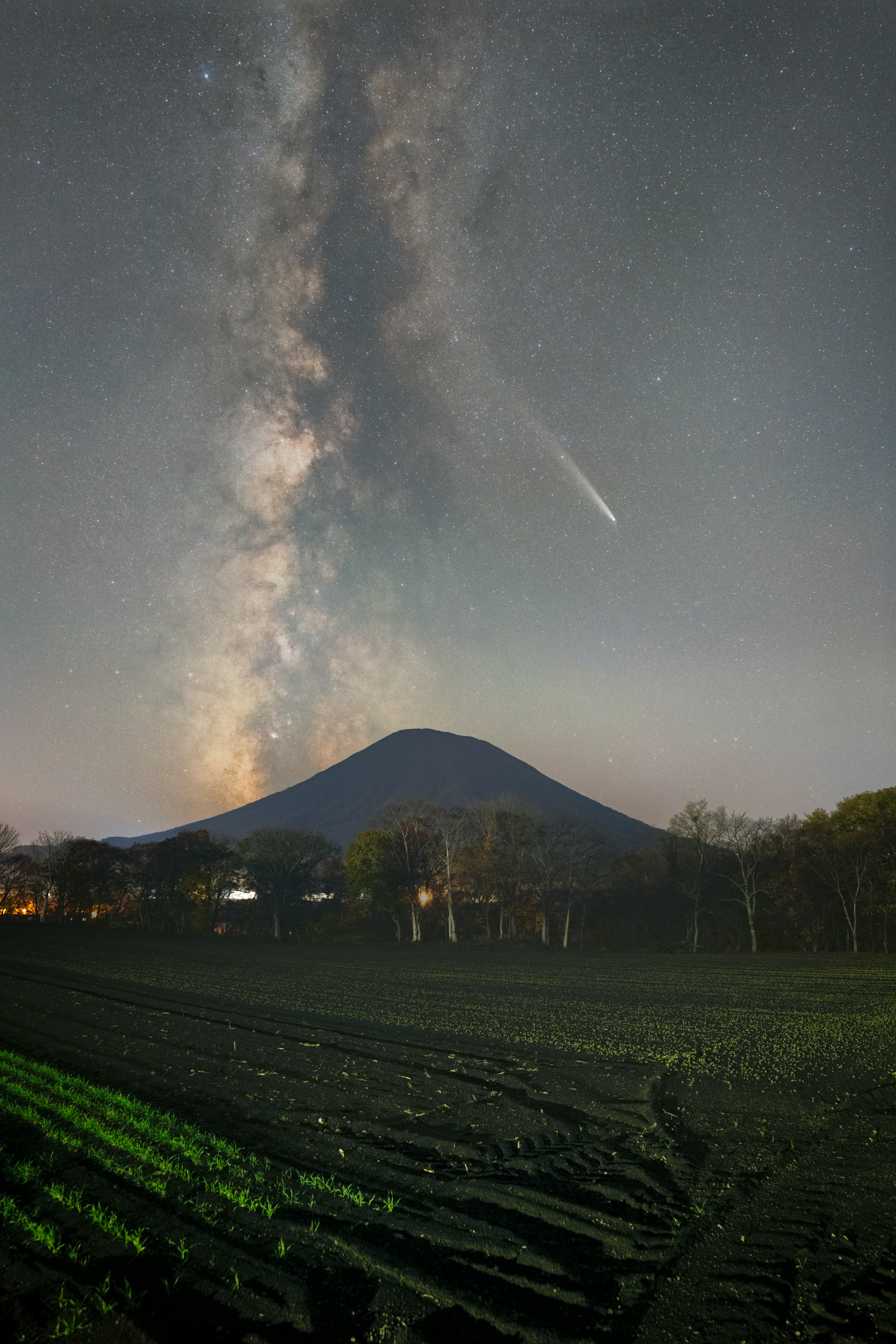 夜の畑とシルエットの山、天の川のような星空