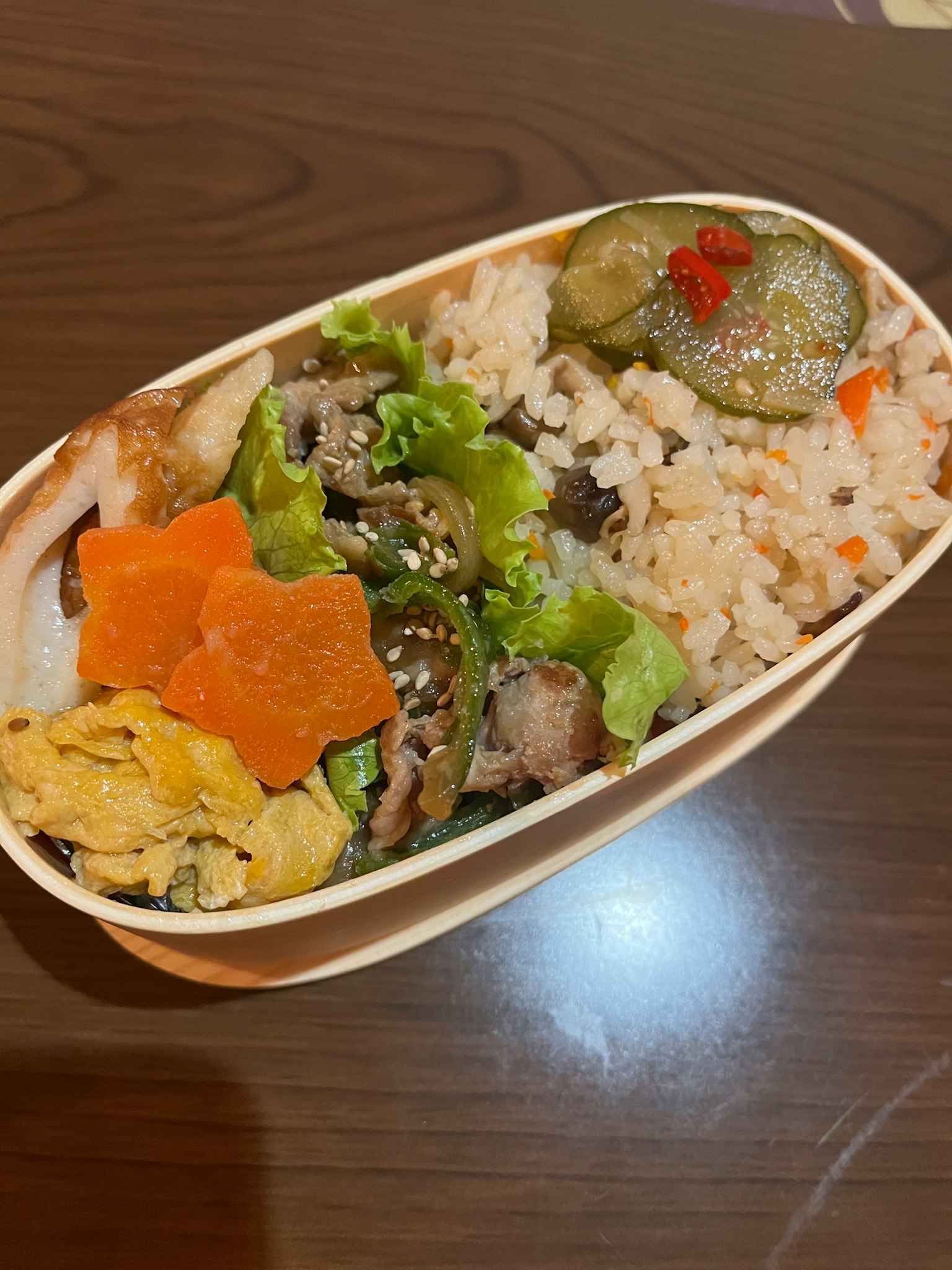 Une boîte à bento avec du riz, des légumes, de la viande et une omelette roulée