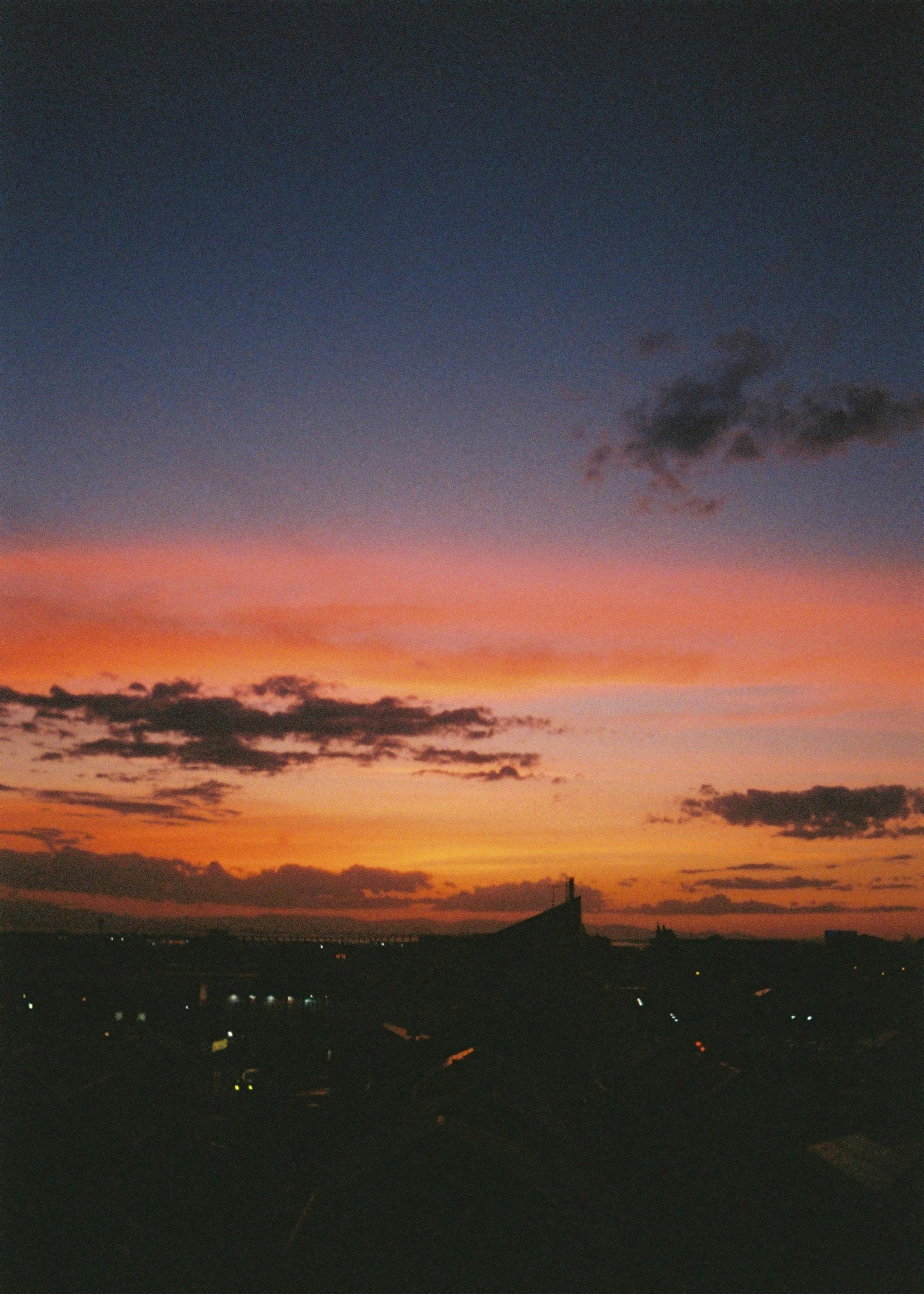 Abendhimmel mit Sonnenuntergang und Stadtlichtern bei Nacht